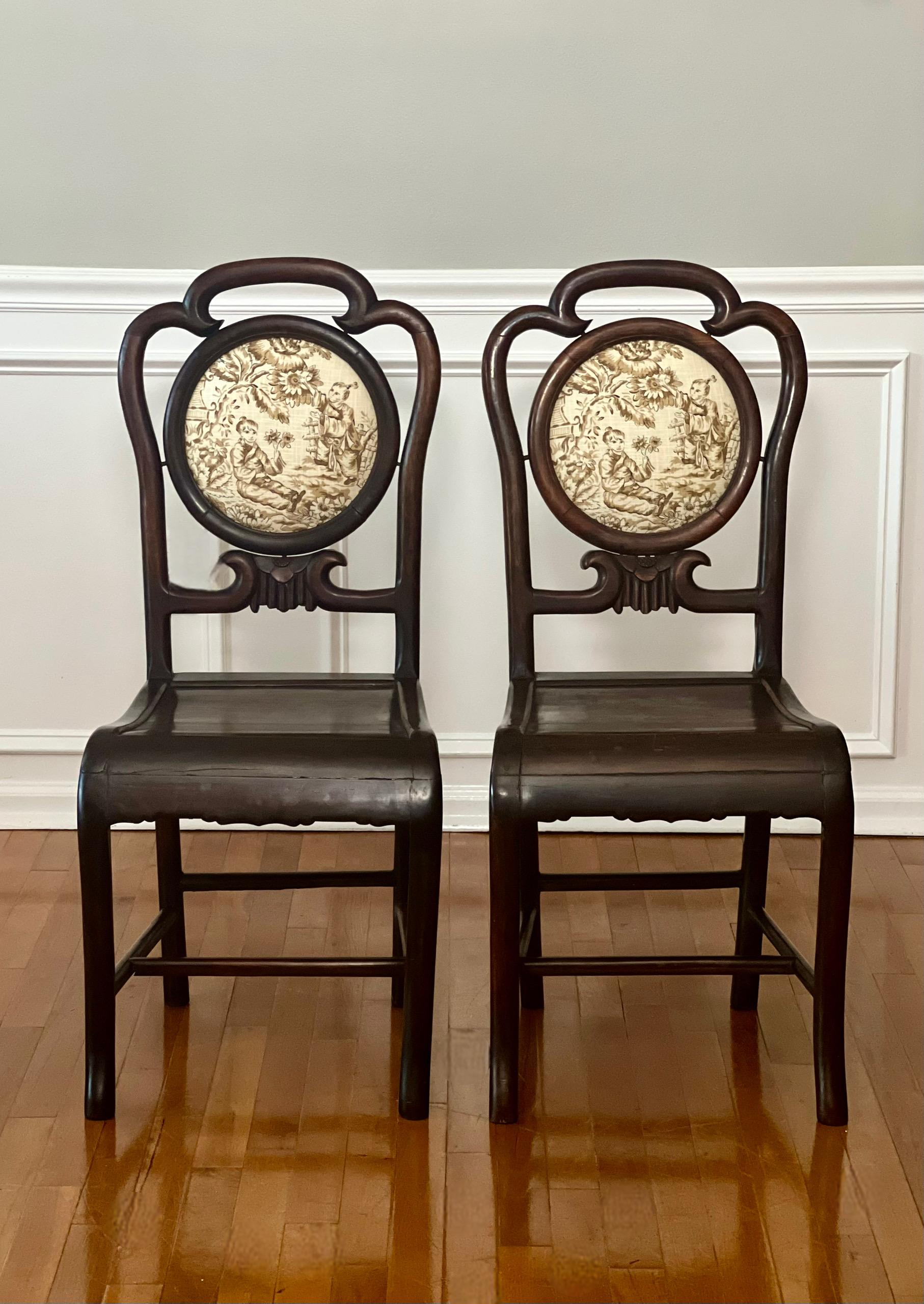Chaises d'appoint ou de salle à manger en palissandre de Chine, avec médaillon en toile de Chinoiserie, vers la fin du 19e siècle. Ils sont dotés d'un dossier à volutes sculptées avec des détails floraux centraux et d'un revêtement en lin crème