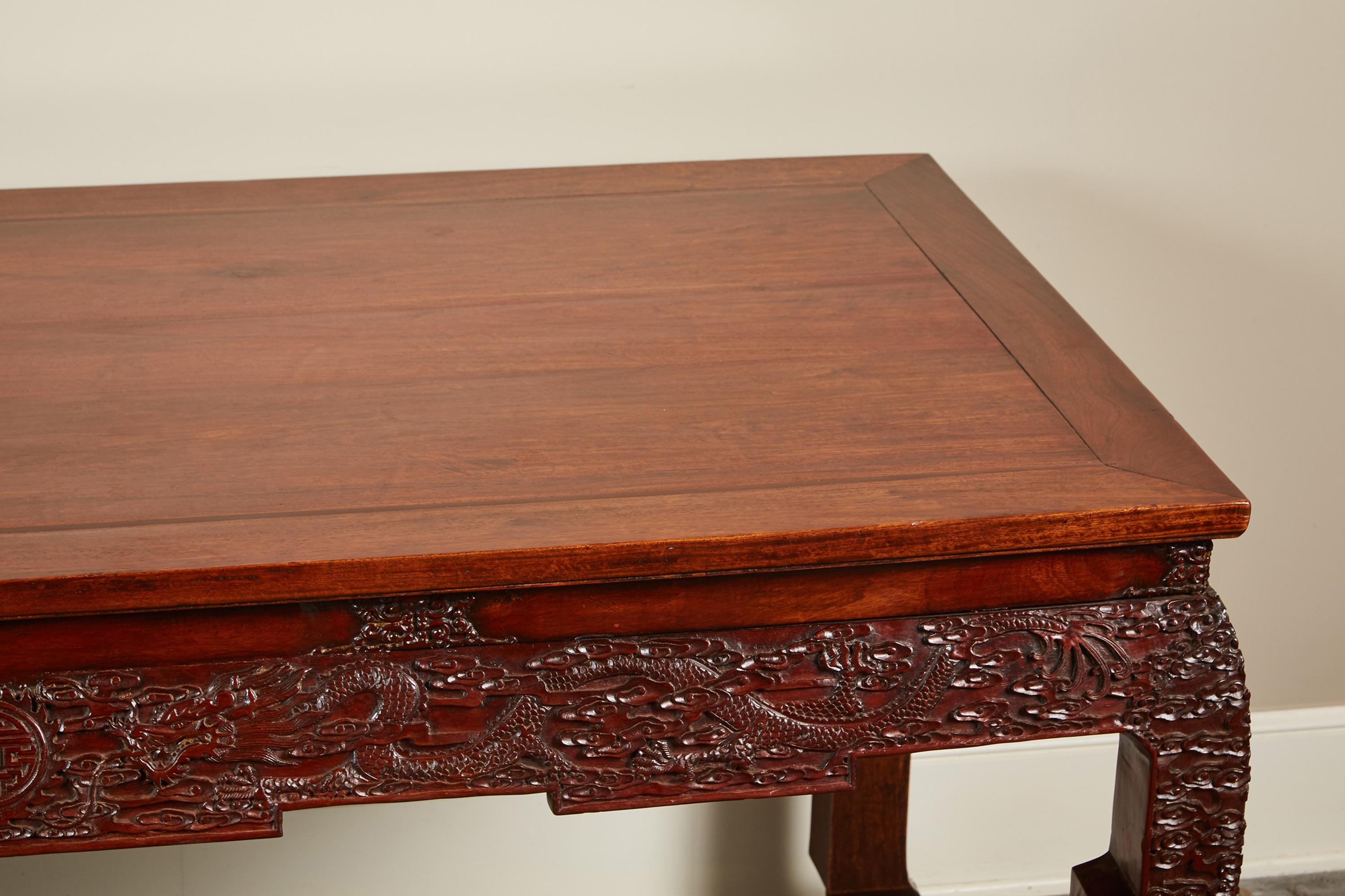 A 19th century Chinese rosewood console table with five-panel top and shaped legs. The apron and upper and lower legs elaborately carved with dragons and repeating cloud motif. Top and bottom is an old marriage.
