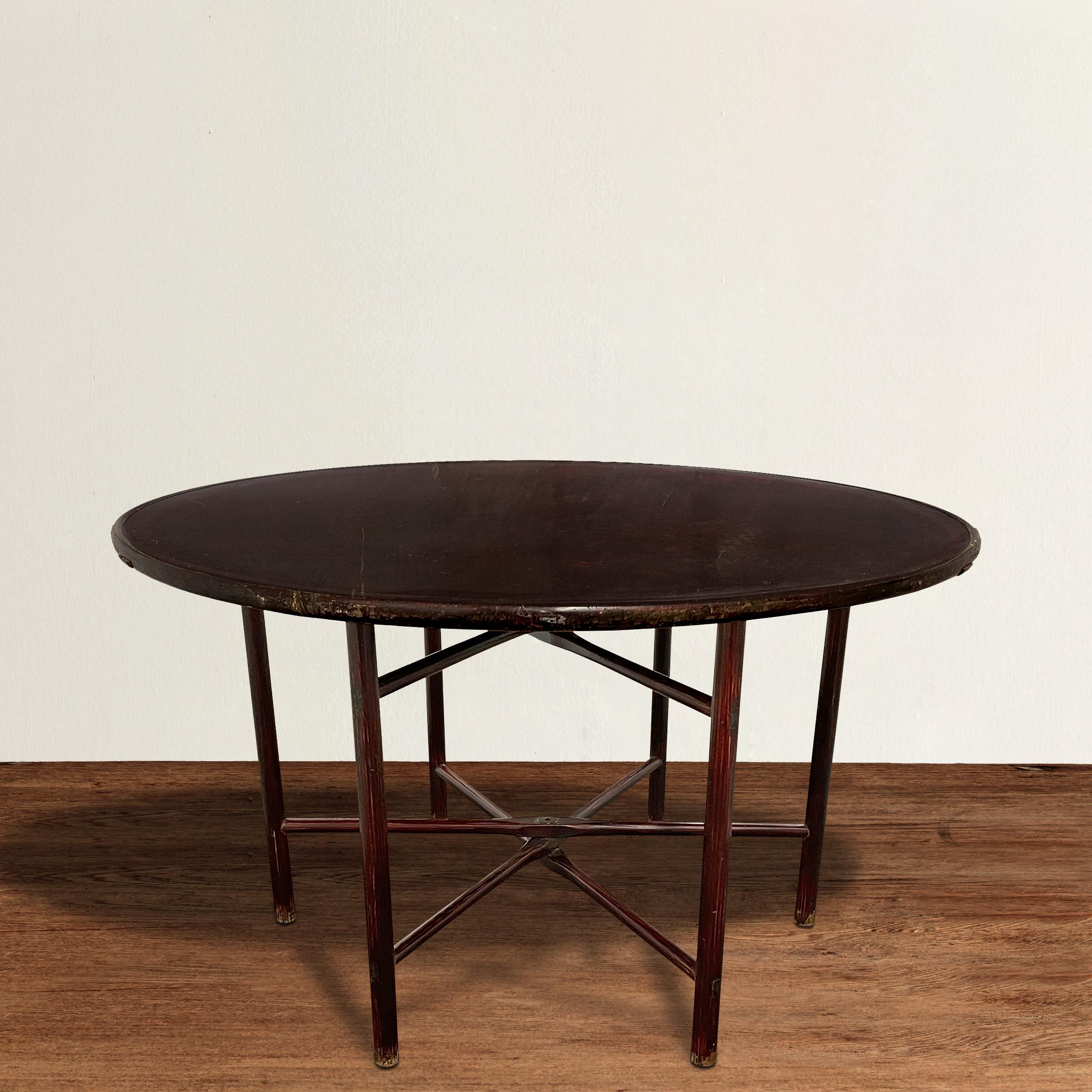 A chic and modern-in-spirit 19th century Chinese elmwood round table with a removable top and collapsible legs, and a fantastic dark sangre-de-boeuf lacquer. Legs can be an easily cut down to make the table standard dining height, or coffee table