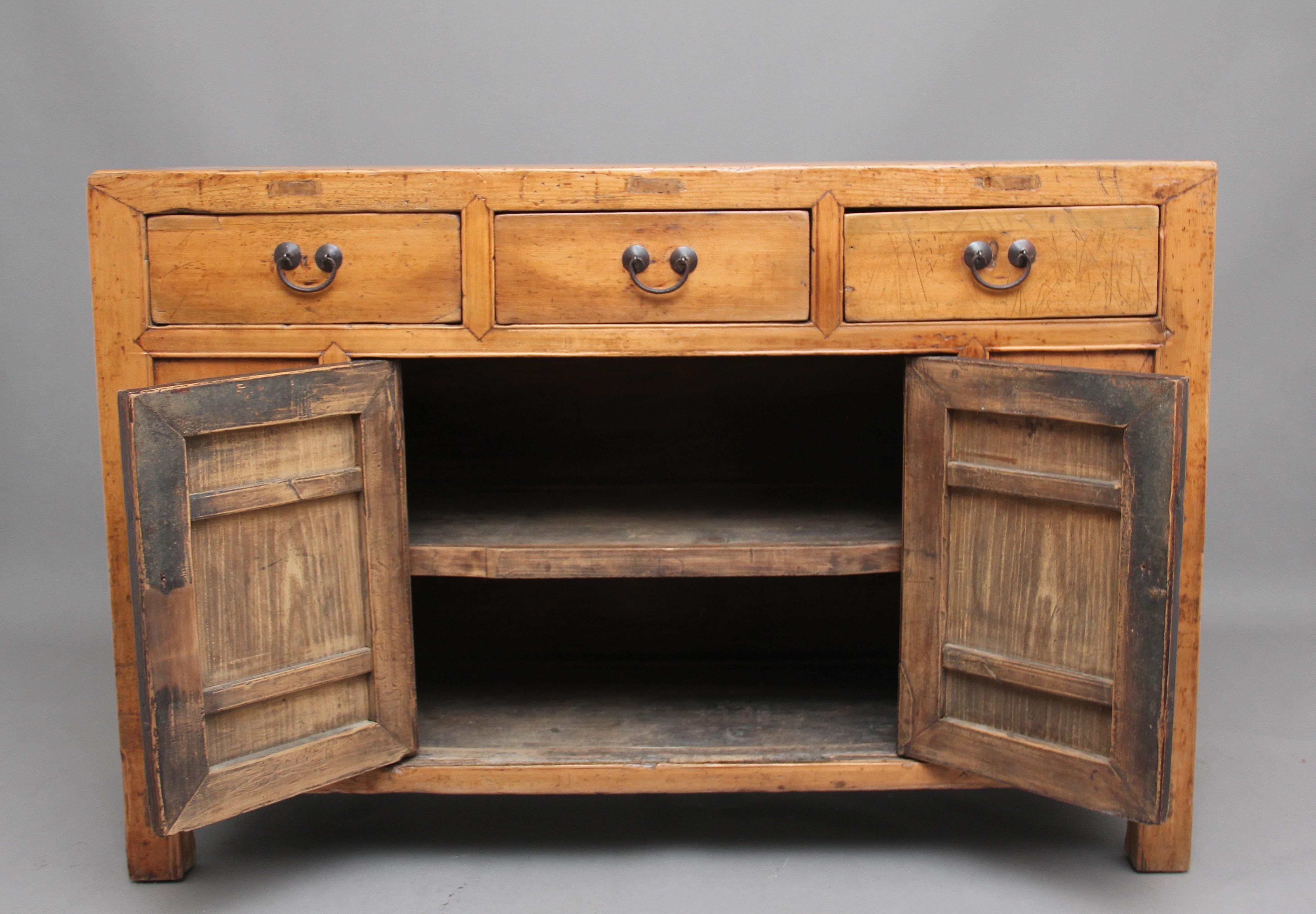 19th century Chinese rustic pine dresser, having three drawers above a two door cupboard opening to reveal a fixed single shelf inside, the drawers and doors having original brass handles, standing on square feet, circa 1880.
      