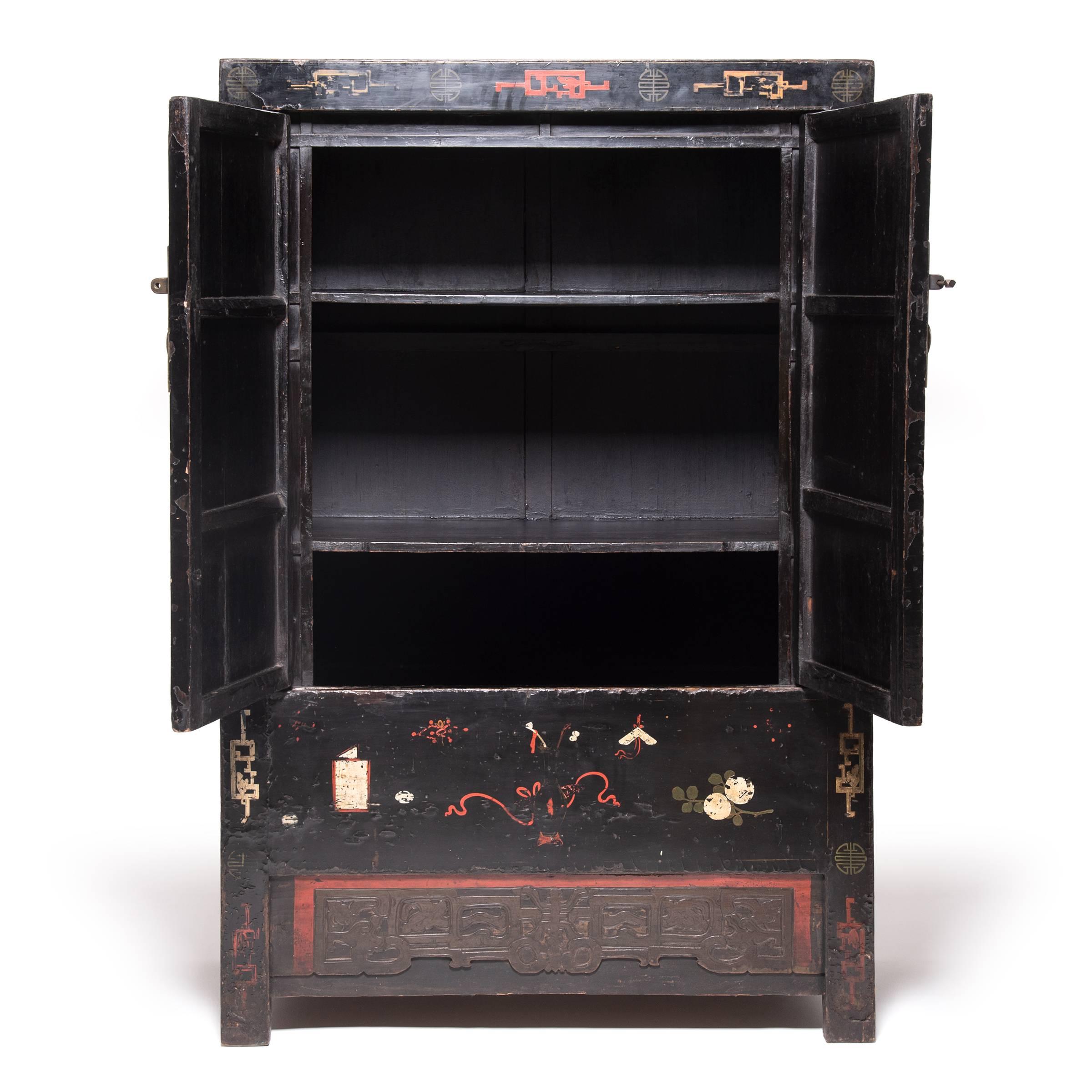 Seamlessly constructed and lacquered black, this spectacular Qing-dynasty cabinet provides the perfect blank canvas for dozens of painted scholars' objects, including vases, censors, brush pots, books and auspicious fruits and flowers. Still vividly
