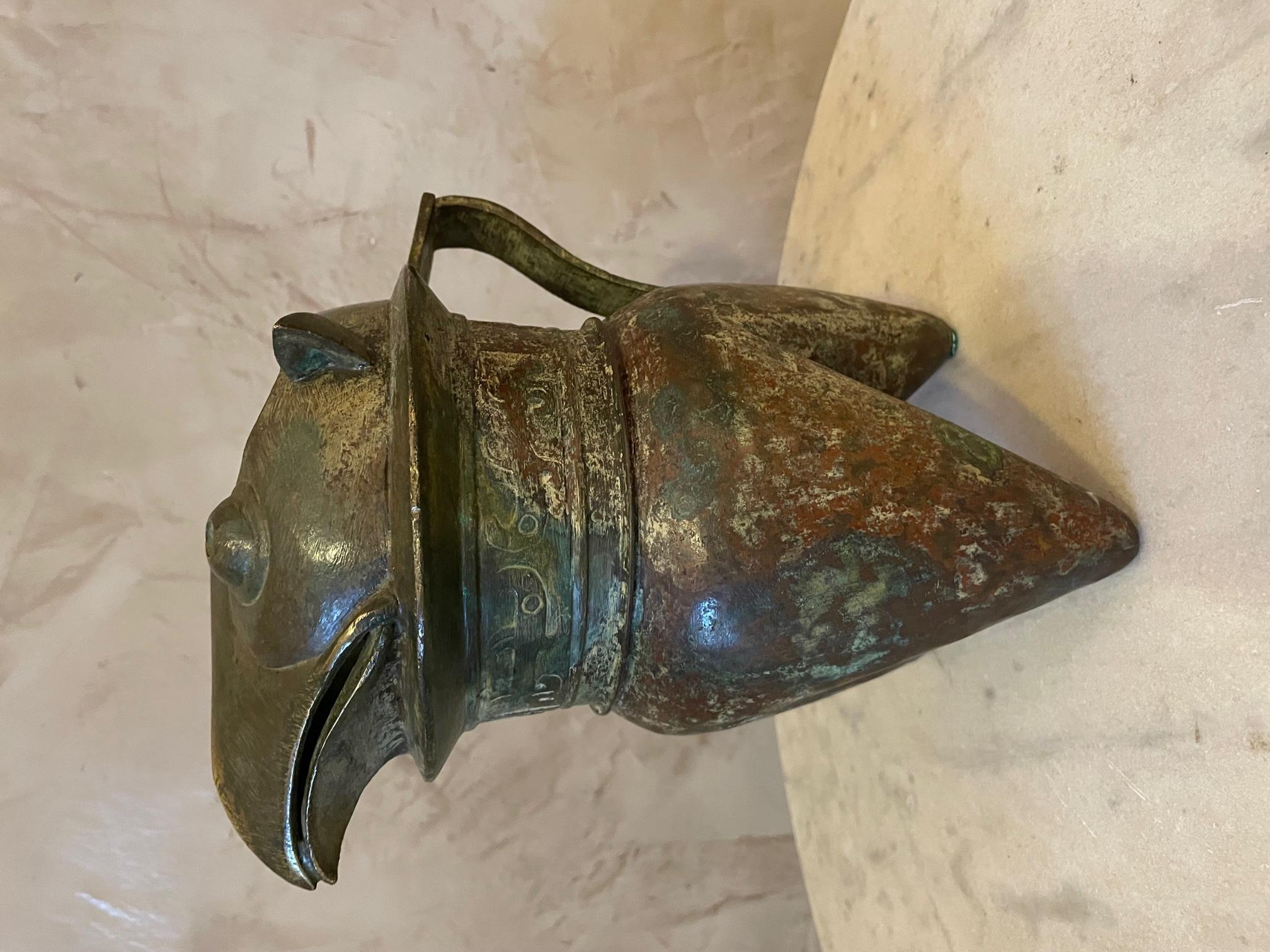 Exceptional reproduction of a he type liquor Jug in bronze of the Shang Dynasty (17th-11th century BC). This bronze jug trypod represent a owl's head. 
We can see symbol frieze just under the head. 
One copy is representing at the Guimet Museum,