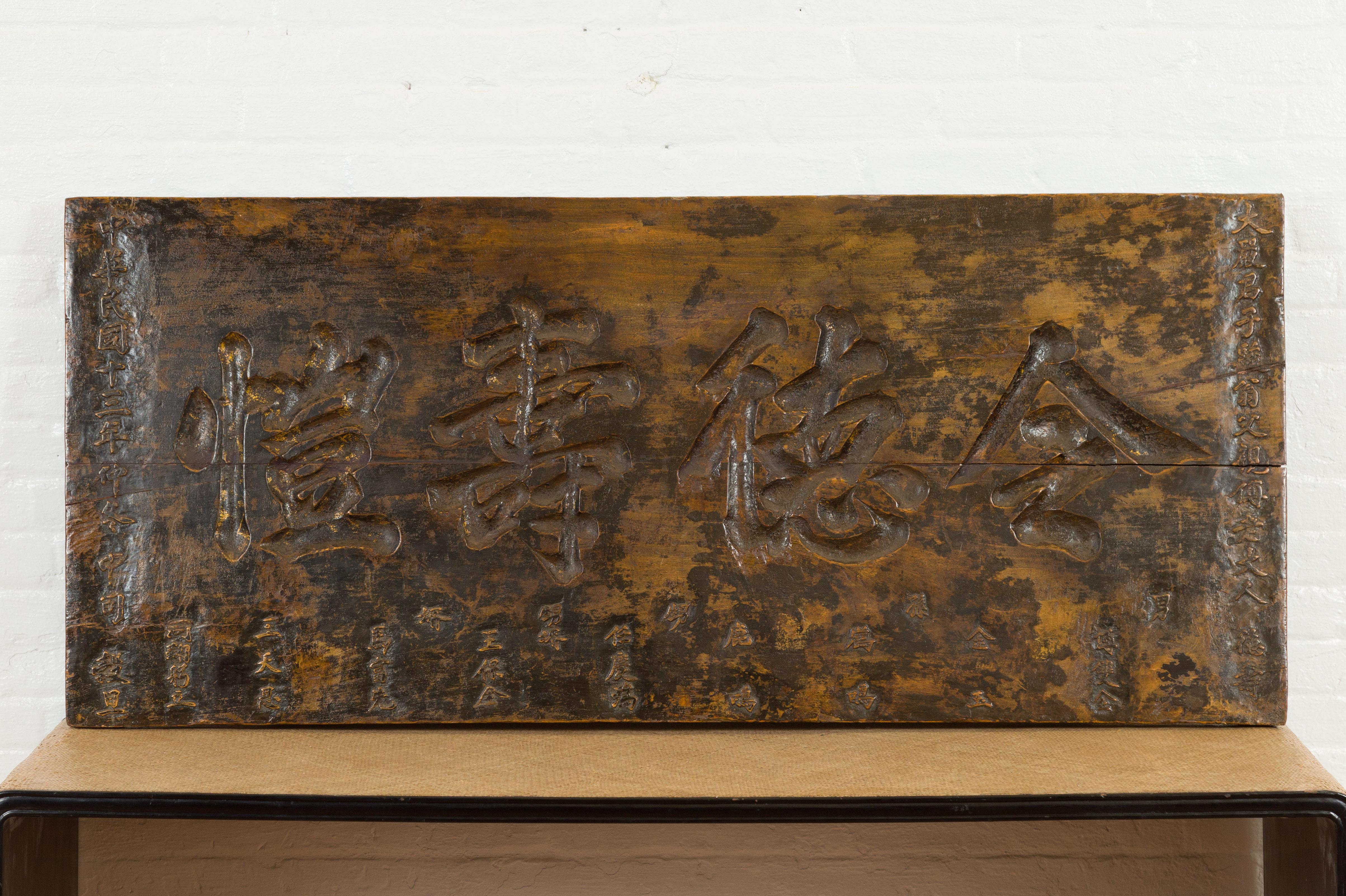 A rectangular Chinese shop sign panel from the 19th century with calligraphy and distressed dark brown patina. Crafted in China, this shop sign features a clean rectangular silhouette, simply adorned with calligraphy. Boasting a dark patina with