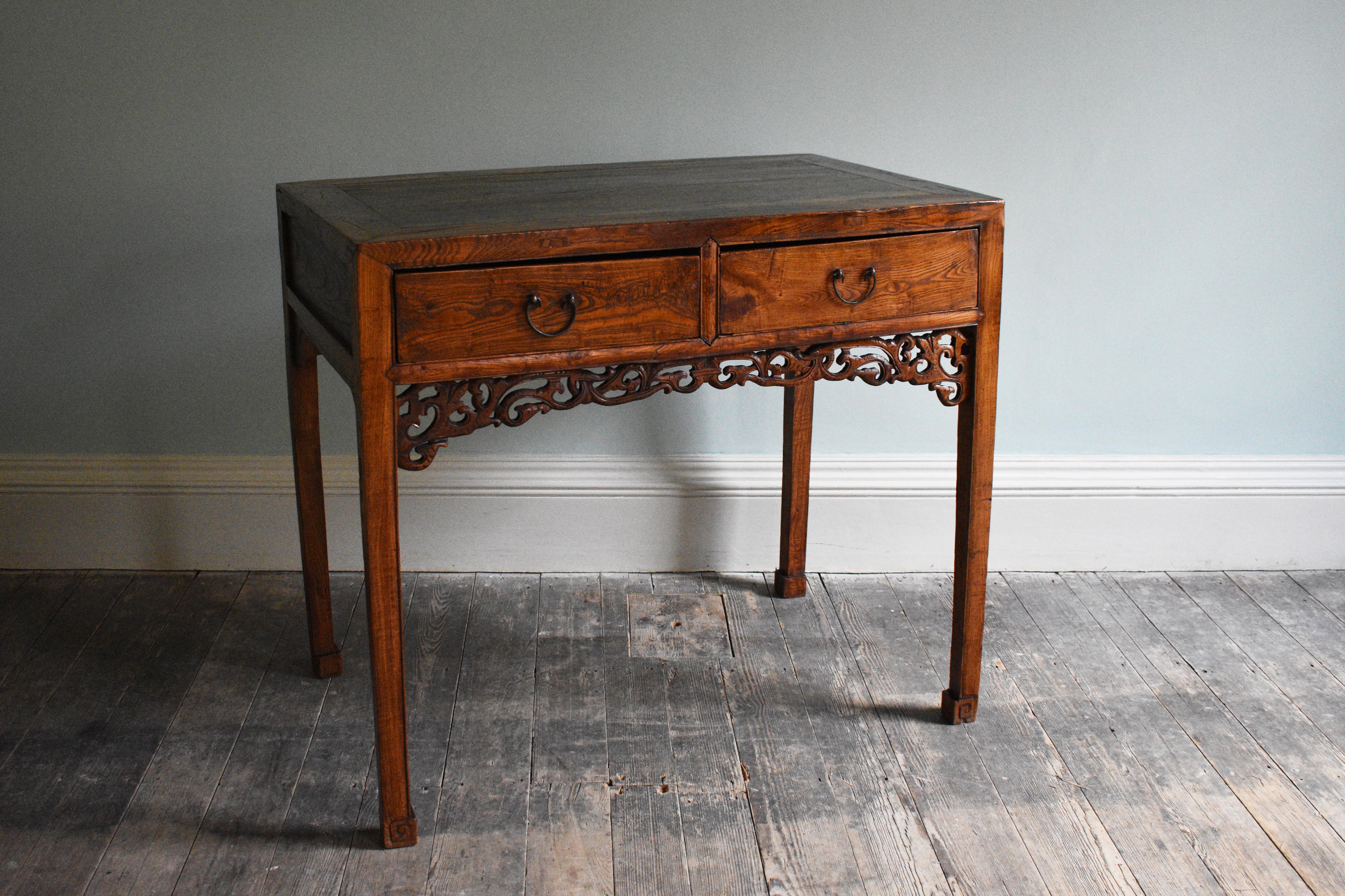 An elegant Chinese side table with ornate open carving flanking two front drawers, 19th century. 

Dimensions: H90 x W101.5 x D62.5 cm.