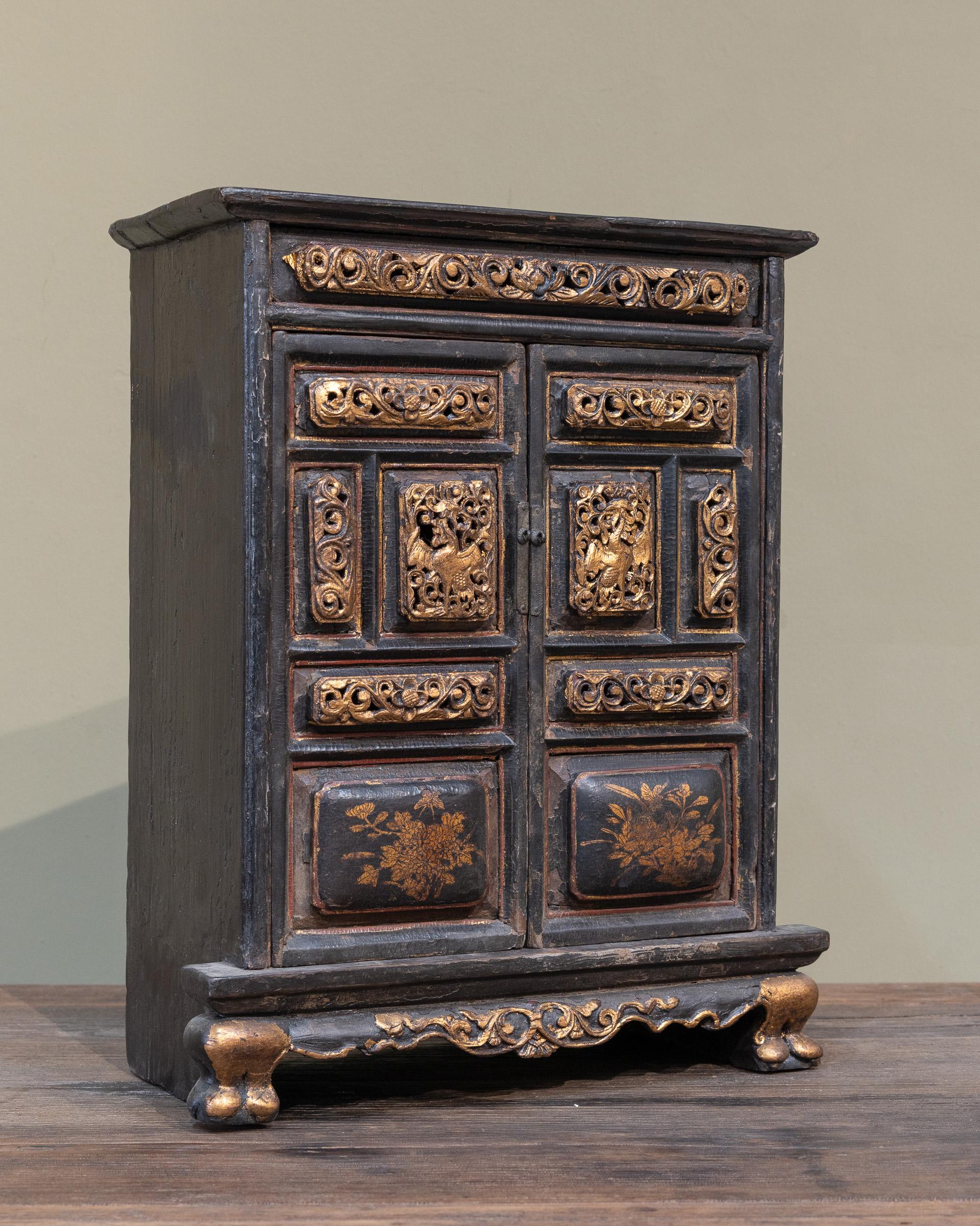 An antique carved box from Chaozhou city, in Guangdong, China. The black and gold colours, as well as the bulbous designs on the front are all distinct characteristics of Chaozhou designs. The main carvings on the doors feature a pair of phoenix,