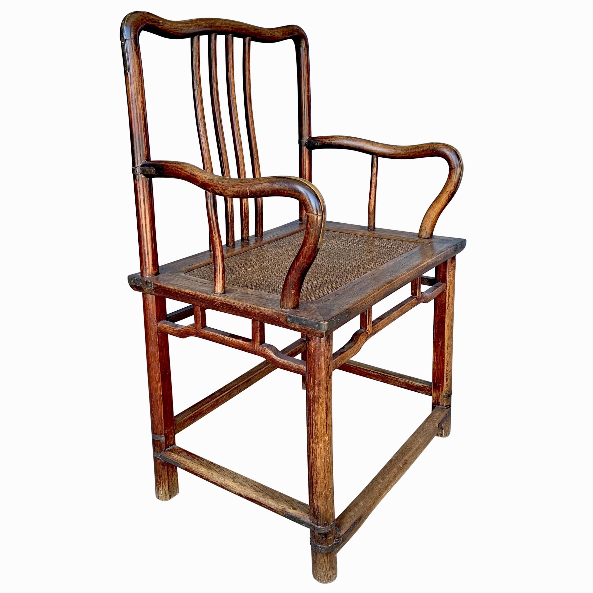 A fine 19th century Chinese huali (rosewood) Southern Administrator's armchair with gently curved crestrail and arms, four-spindle backsplat, brass fittings, woven cane seat, and traces of the original sangre-de-boeuf glaze.