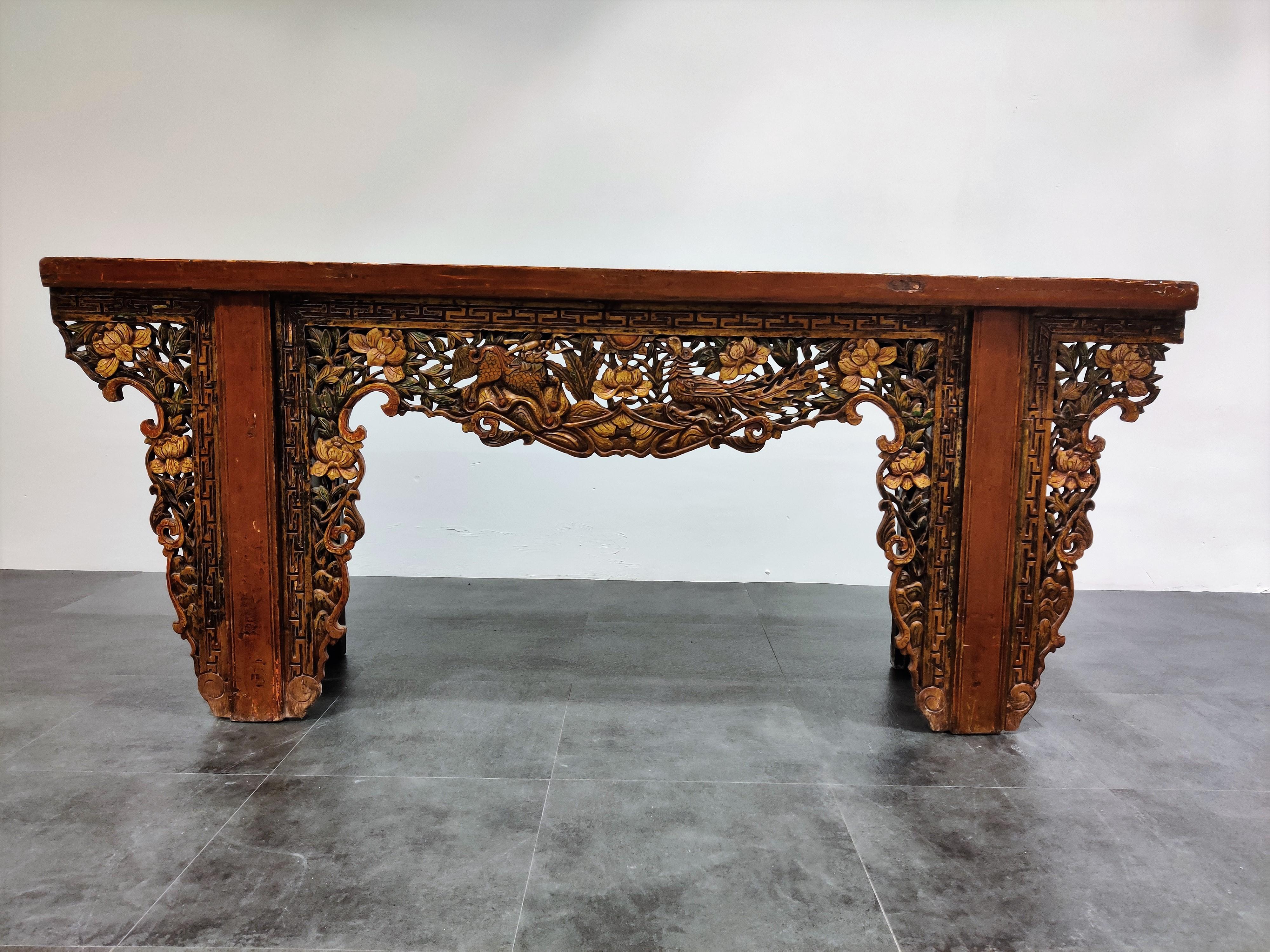 A Chinese altar table.

The oblong plank top above two massive end supports with a shaped apron and brackets elaborately carved with flowering lotus, a Kylin and Ho-Ho Bird.

The timber is difficult to discern, but likely to be a stained