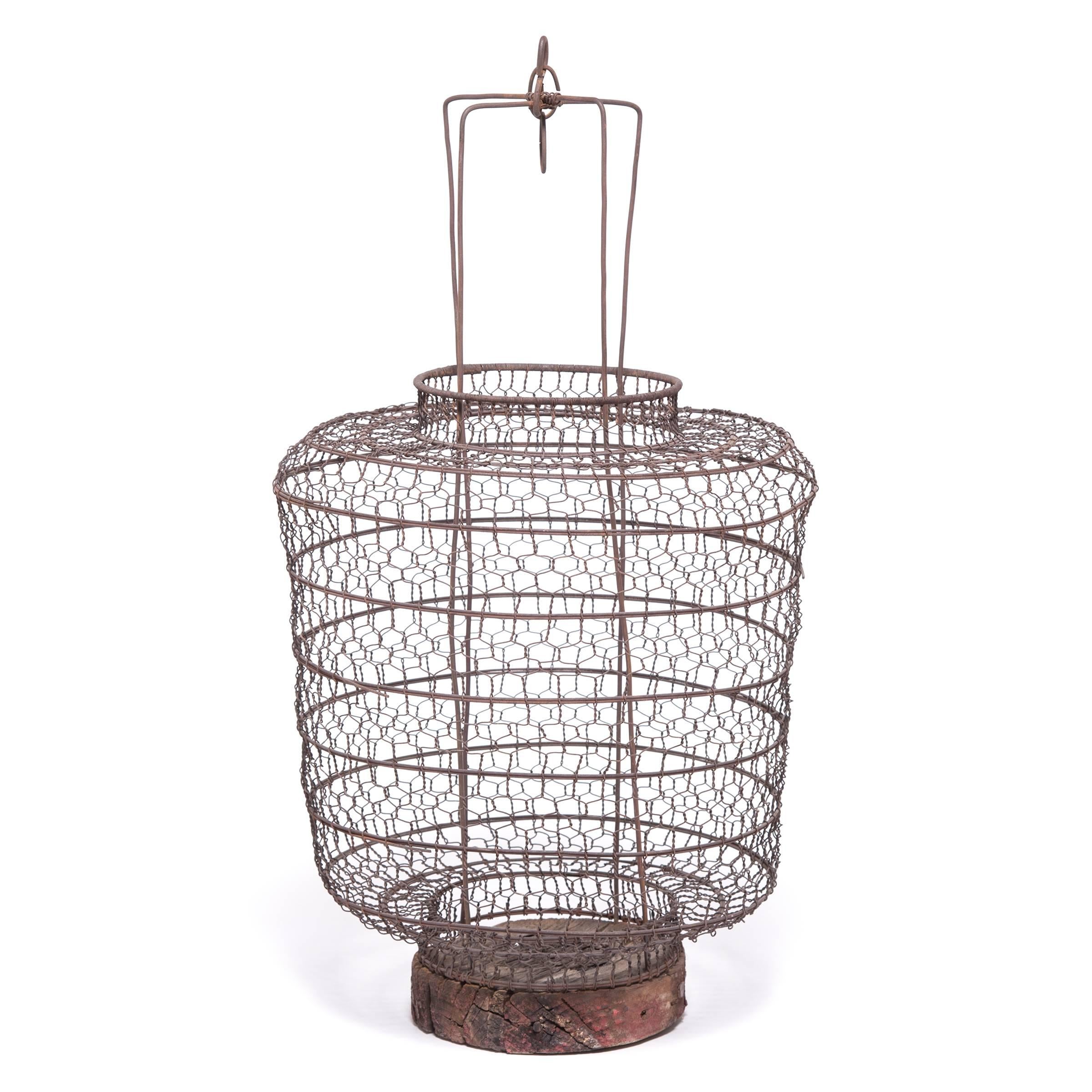 This 19th century lantern once hung from a small boat, illuminating the waters for nighttime fishing. Handwoven from iron wire, the lantern has a lacy, open pattern and may have been lined with fabric or paper to provide protection from wind.