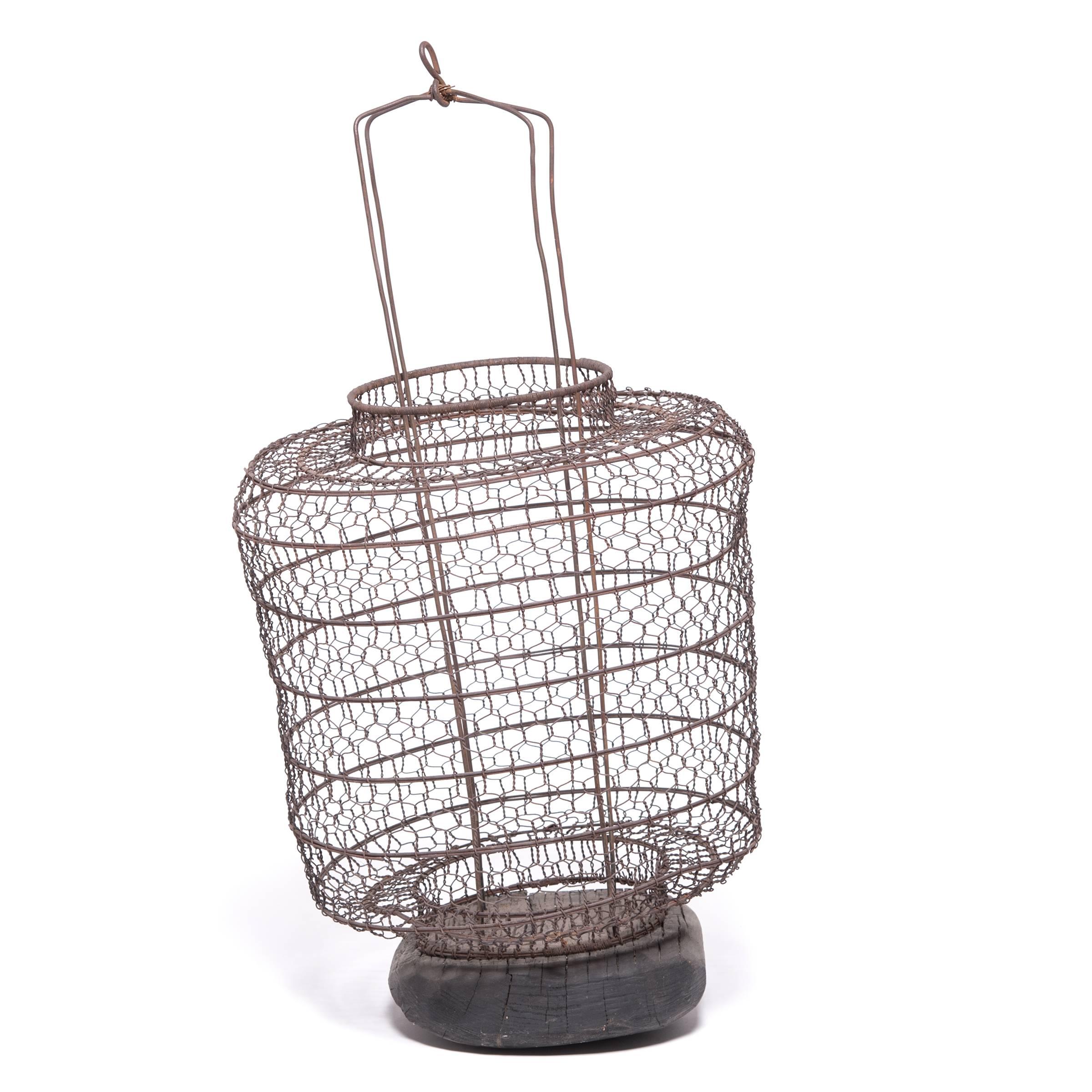 This 19th century lantern once hung from a small boat, illuminating the waters for nighttime fishing. Handwoven from iron wire, the lantern has a lacy, open pattern and may have been lined with fabric or paper to provide protection from wind.