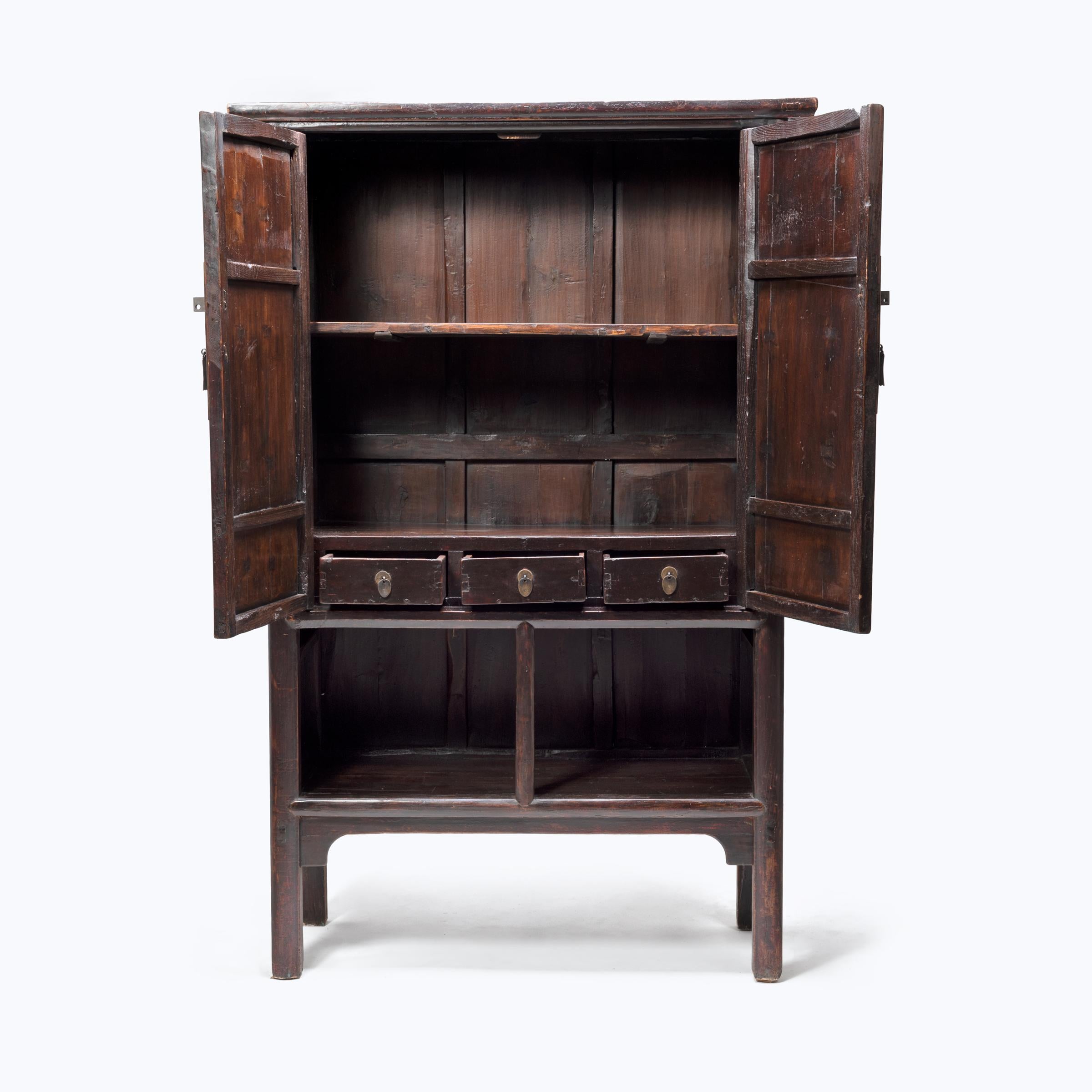 Classic Chinese furniture design is characterized by the flawless construction, purity of line, and dedication to detail you see here in this two-door cabinet. This beautiful elmwood cabinet was created in the mid-19th century by an artisan from