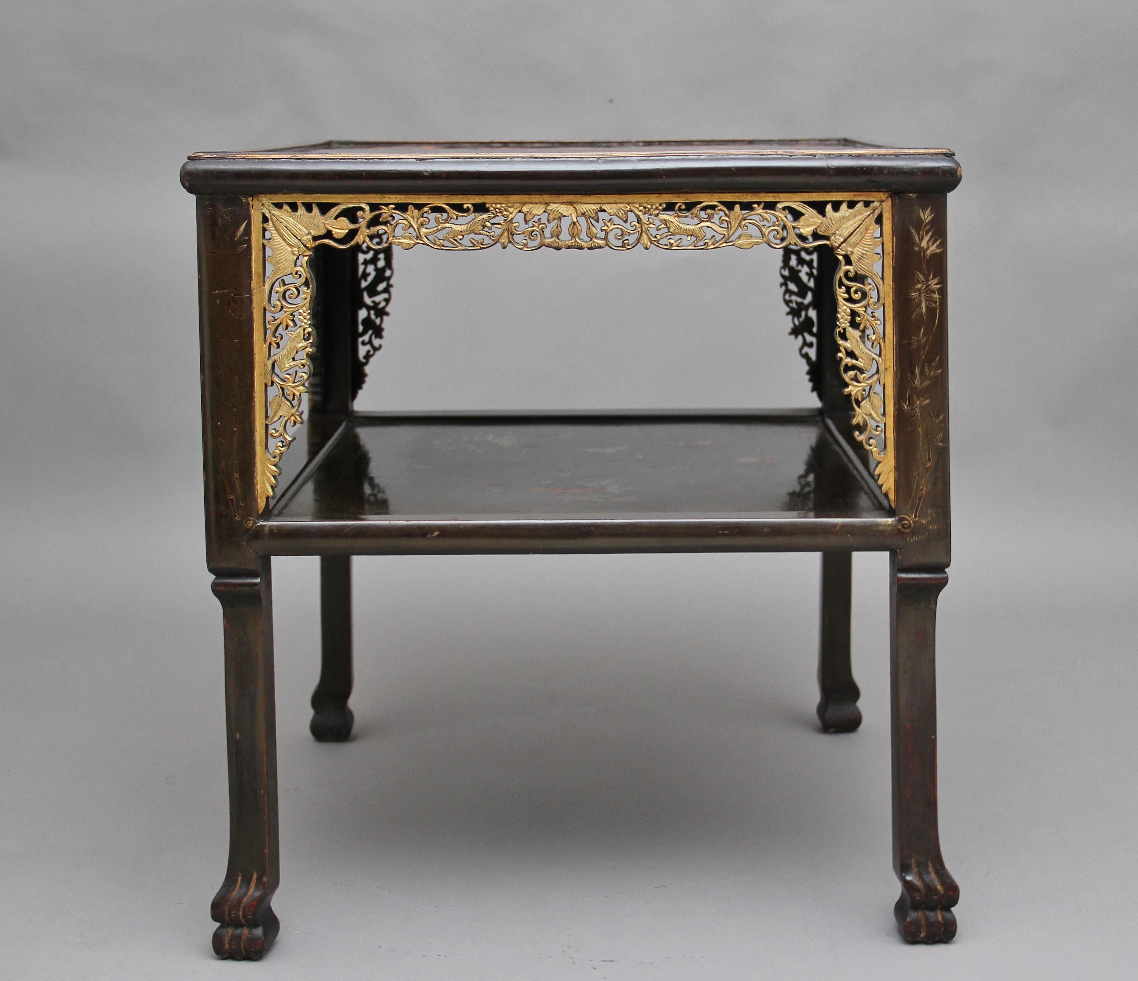 A decorative 19th century Chinese lacquered two-tier occasional table, the square top having lovely floral pattern decoration and this is also the same on the shelf below, each side having detailed carved and gilt fret work, supported on square legs