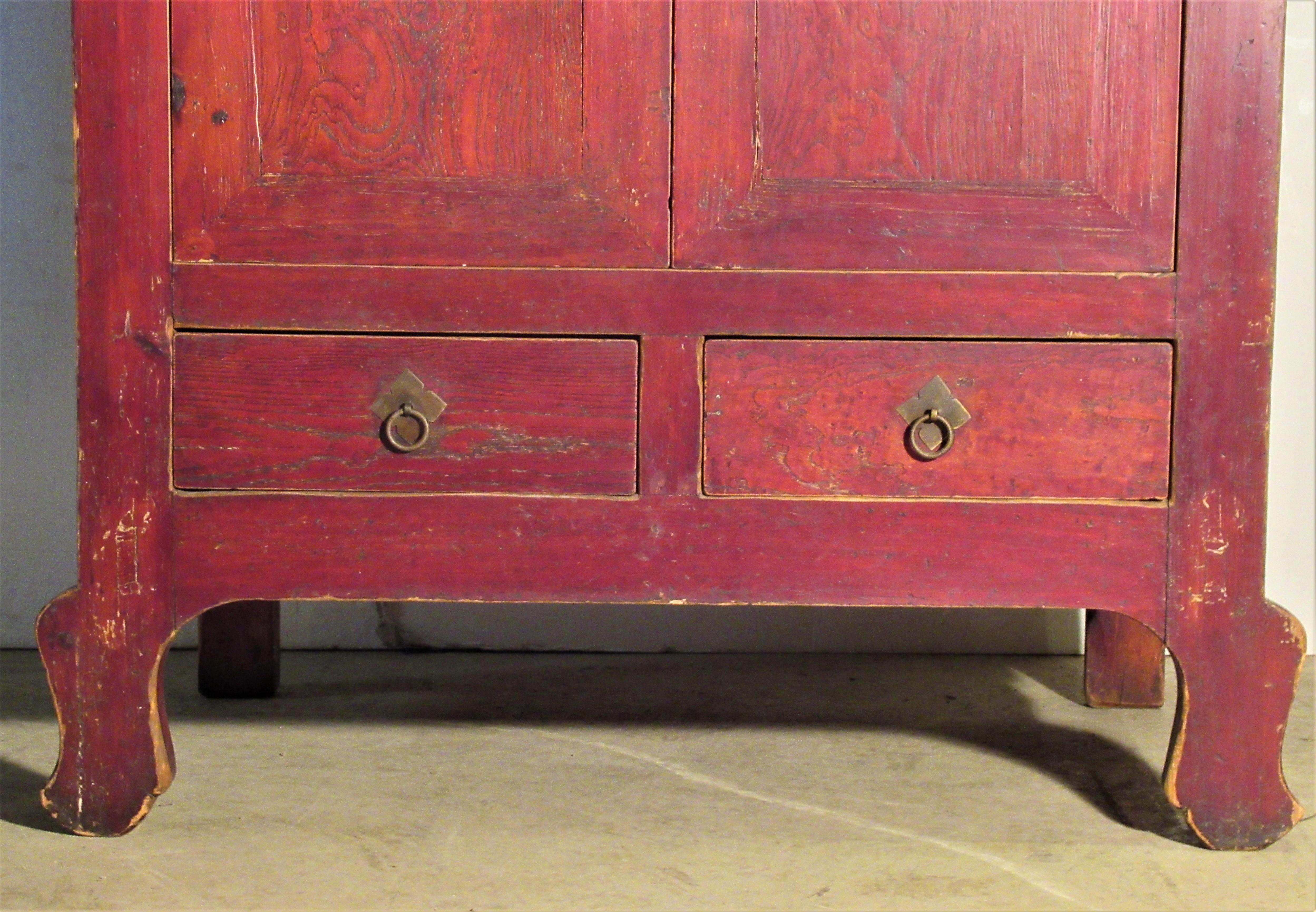 Antique Chinese wedding cabinet in beautifully aged all original burnt sienna red stained finish that nicely compliments the grain of wood. Two doors over two drawers / brass hardware / ink painted decoration of bamboo plant at both sides / open