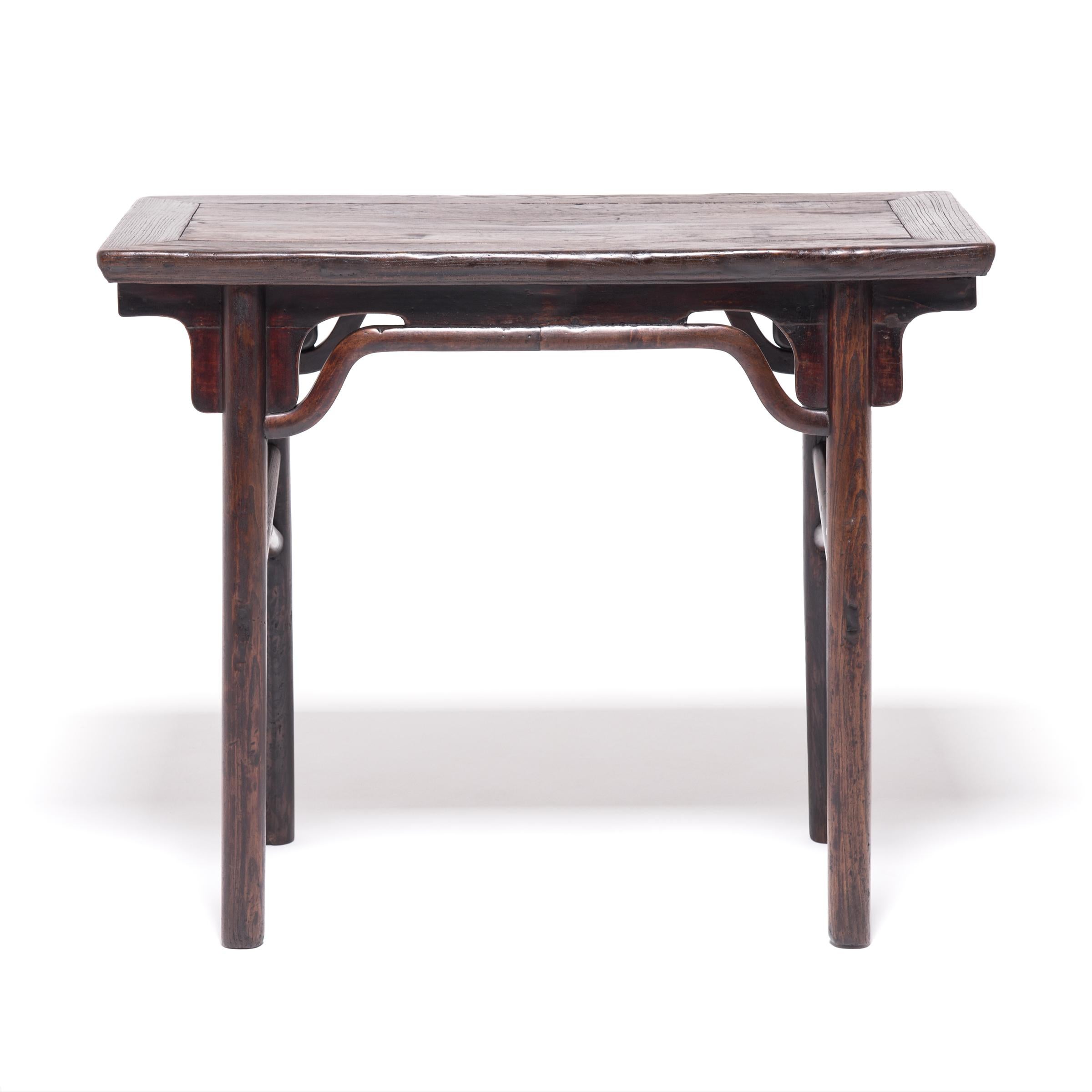 Crossed stretcher bars and apron curves animate the square profile of this elmwood table. Made in Hebei province circa 1850, the beautifully preserved table was used for sharing wine and spirits. Imbibers would gather around the table and engage in