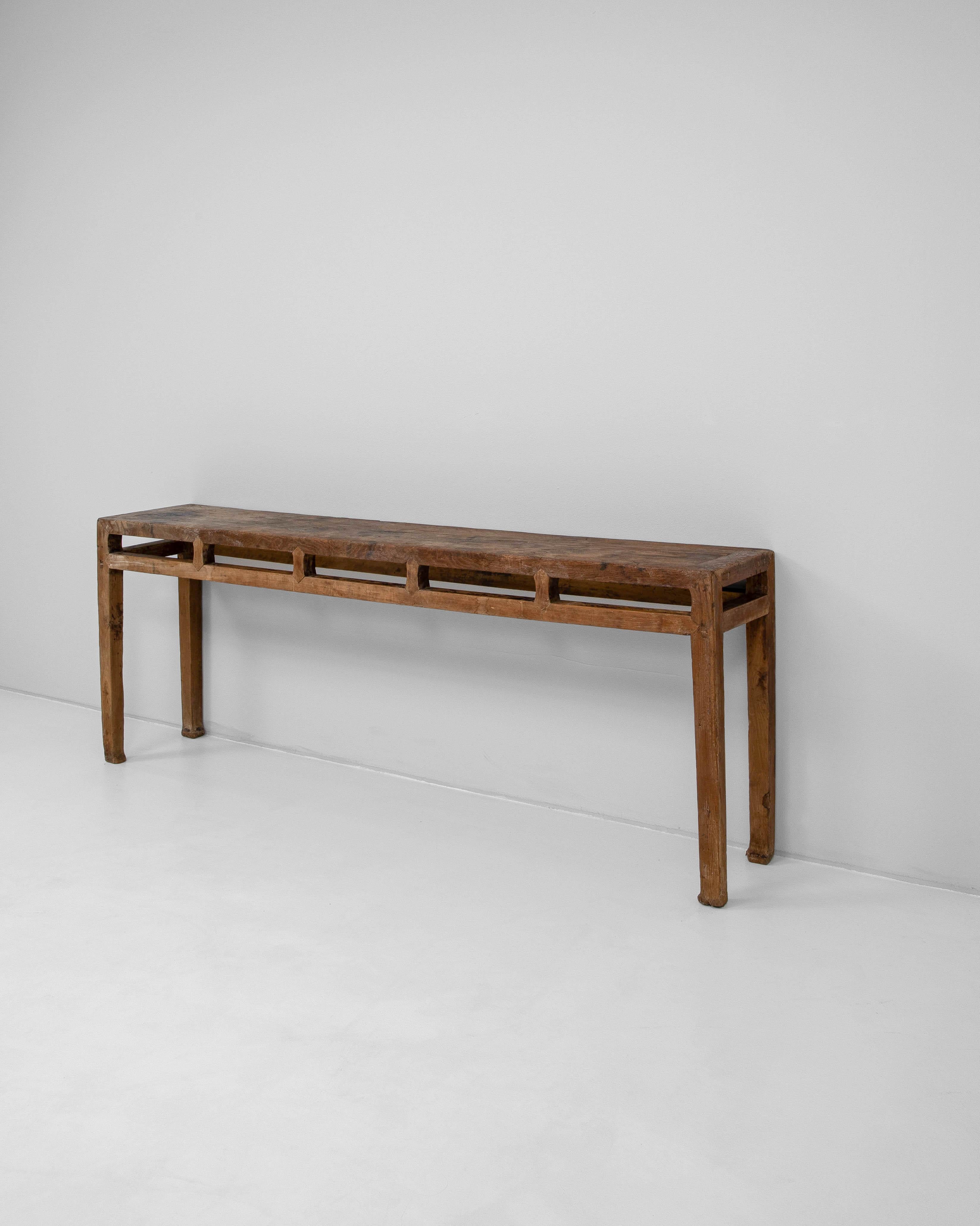 This 19th Century Chinese wooden console is a refined example of traditional craftsmanship, showcasing both elegance and utility. Handcrafted from solid wood with a beautifully aged patina, the console features clean, linear proportions accented by