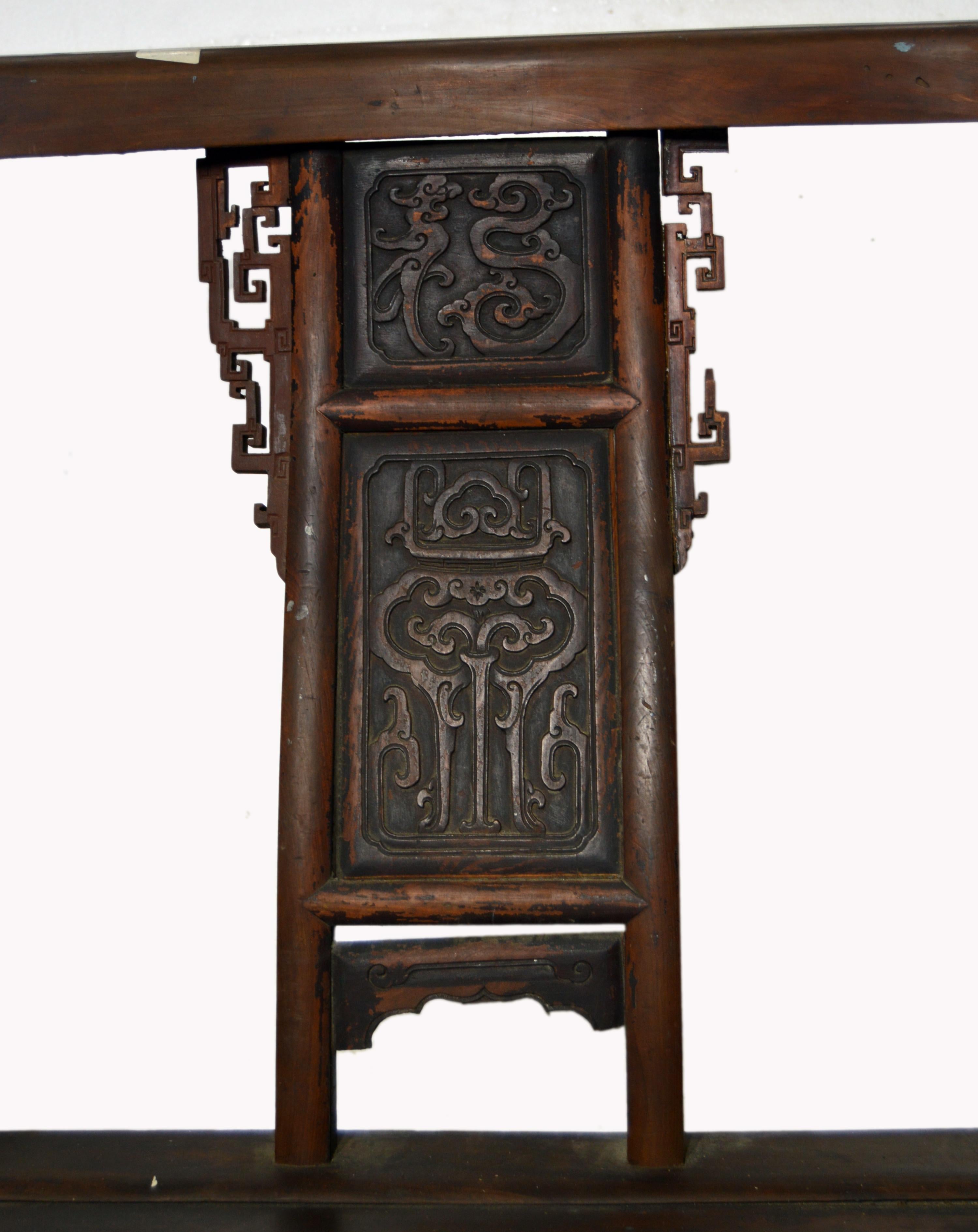 A Chinese hand-carved yumu wood 'Official's Chair' from the 19th century, with fretwork and lacquered finish. This Chinese armchair features a rectangular pierced back accented with an exquisite carved splat, adorned with geometrical scrolls,