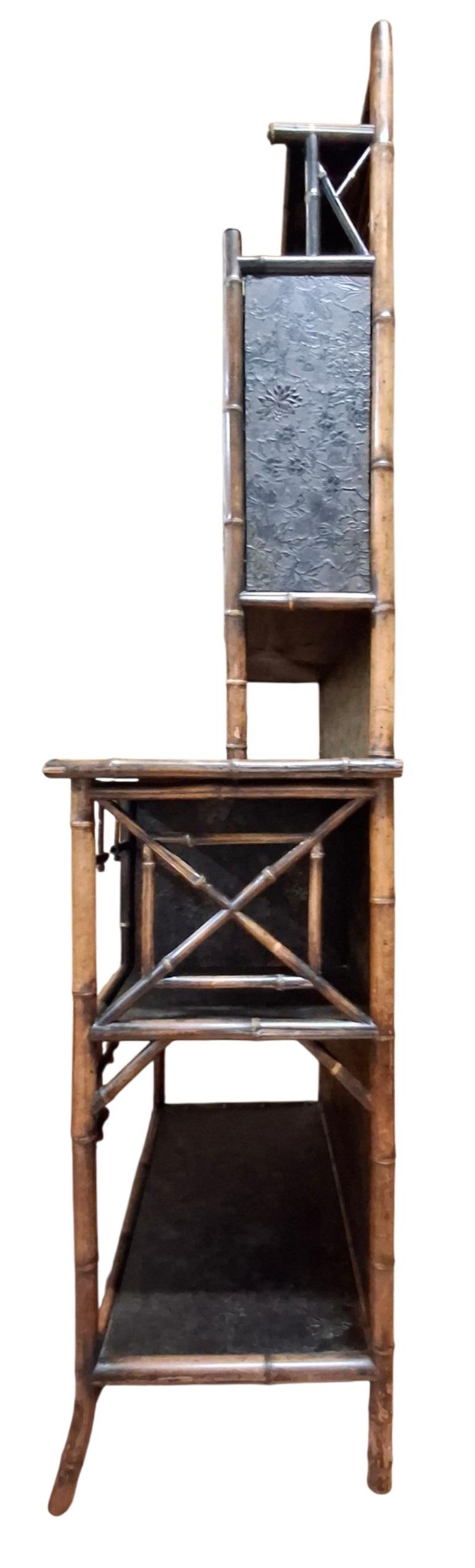Precioso armario/étagère inglés de laca y bambú con galería superior que tiene dos pequeños estantes encima de un armario con puertas de cristal.  Pequeño armario debajo con puertas lacadas pintadas con pájaros y flores, y otros dos espacios de