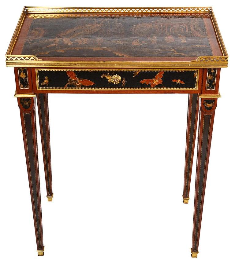 A very decorative early 19th century French Chinoiserie lacquer, ormolu mounted side table, having a three quarter brass gallery around the lacquer top, depicting a classical Chinese scene of a pagoda house and various figures walking down a path.