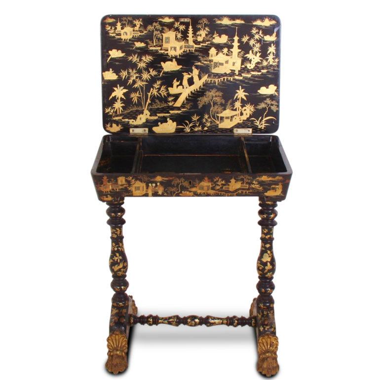 A mid-19th century ladies work or sewing table in black lacquer and profusely decorated with finely painted gilt and red landscape scenery, figures, birds etc. The piece stands on turned legs each without swept legs terminating in ornately carved