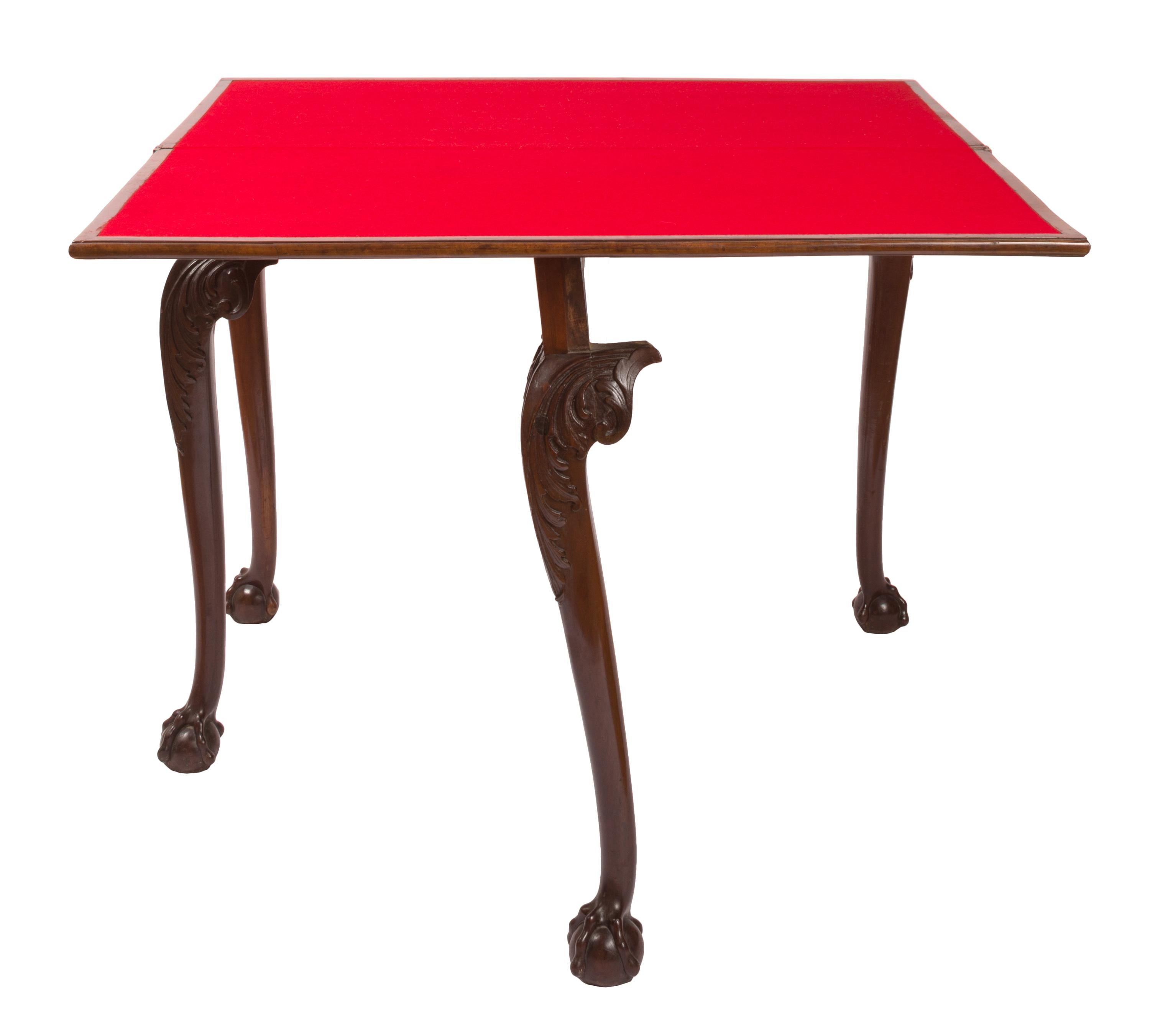 A 19th century Chippendale style swivel fold-over card table that cleverly transforms from a narrow side table into a square, red felt-covered gaming surface. The slender and elegant cabriole legs are decorated with carved acanthus type leaves at