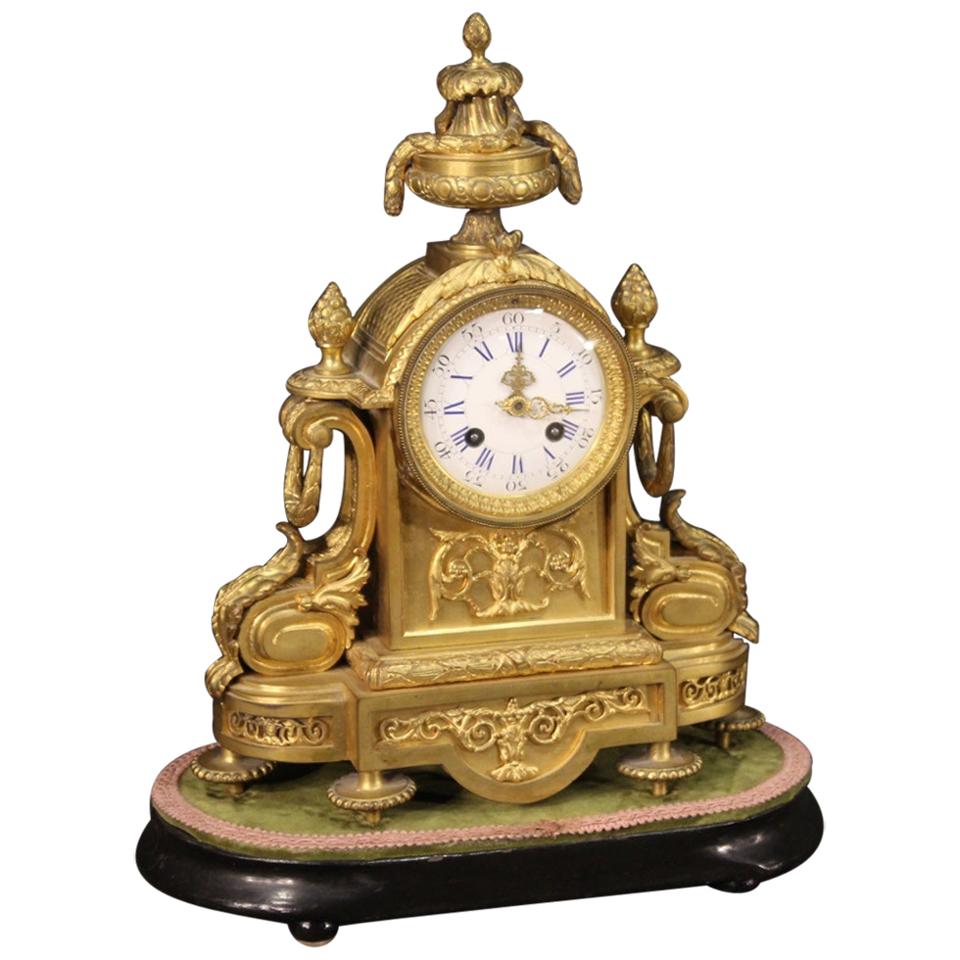 Italian clock from the late 19th century. Finely chiseled and gilded bronze and brass object with enamelled ceramic dial (see picture) and gilt and chiseled brass hands (see picture), complete with key. Clock with ebonized wooden base with velvet
