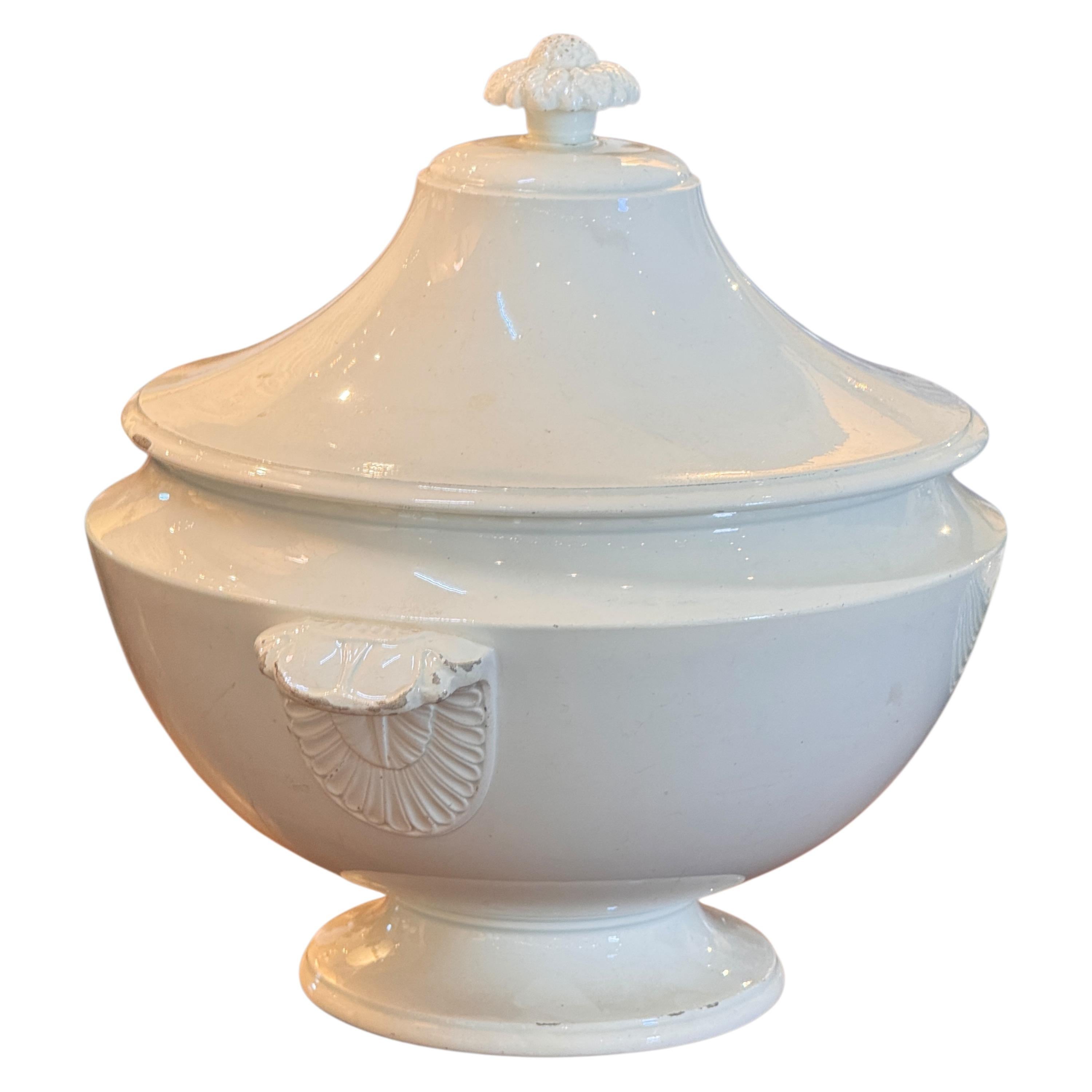 Large French faience tureen from Choisy-le-Roi, late 19th century. The classic white glaze highlights the graceful footed form and domed lid, while the shell-motif handles provide sculptural detail. One handle retains visible wear consistent with