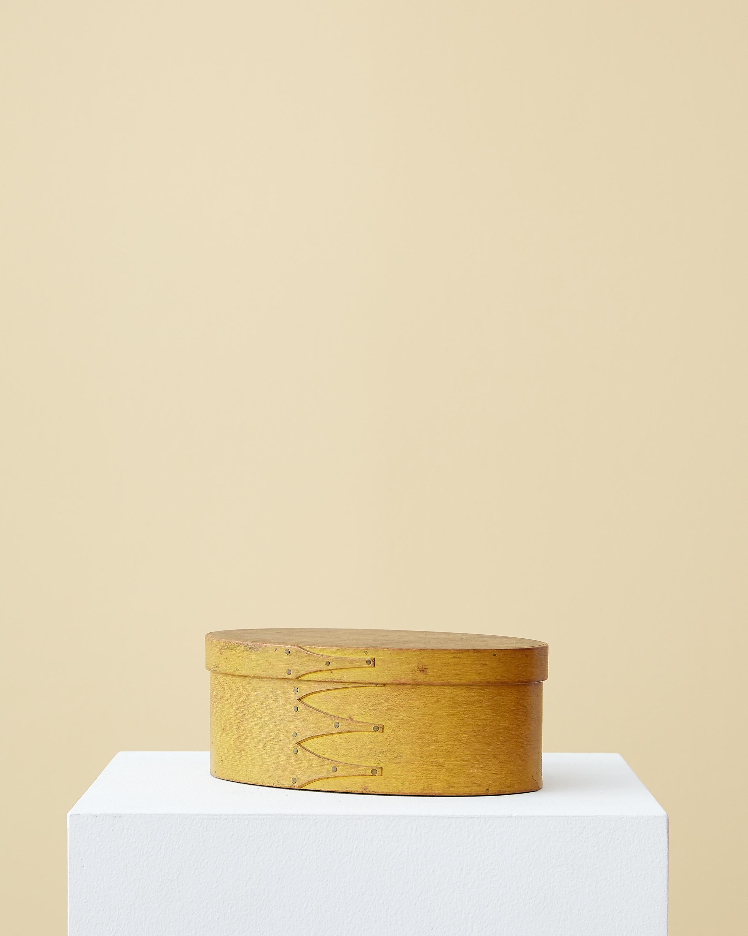 Oval Shaker box in chrome yellow paint with four swallowtail joints. 

Northeastern United States, 19th century. 

Completely original, dry, untouched surface.

Measurements: 3 1/8” height, 8 3/8” length, 5 7/16” depth
