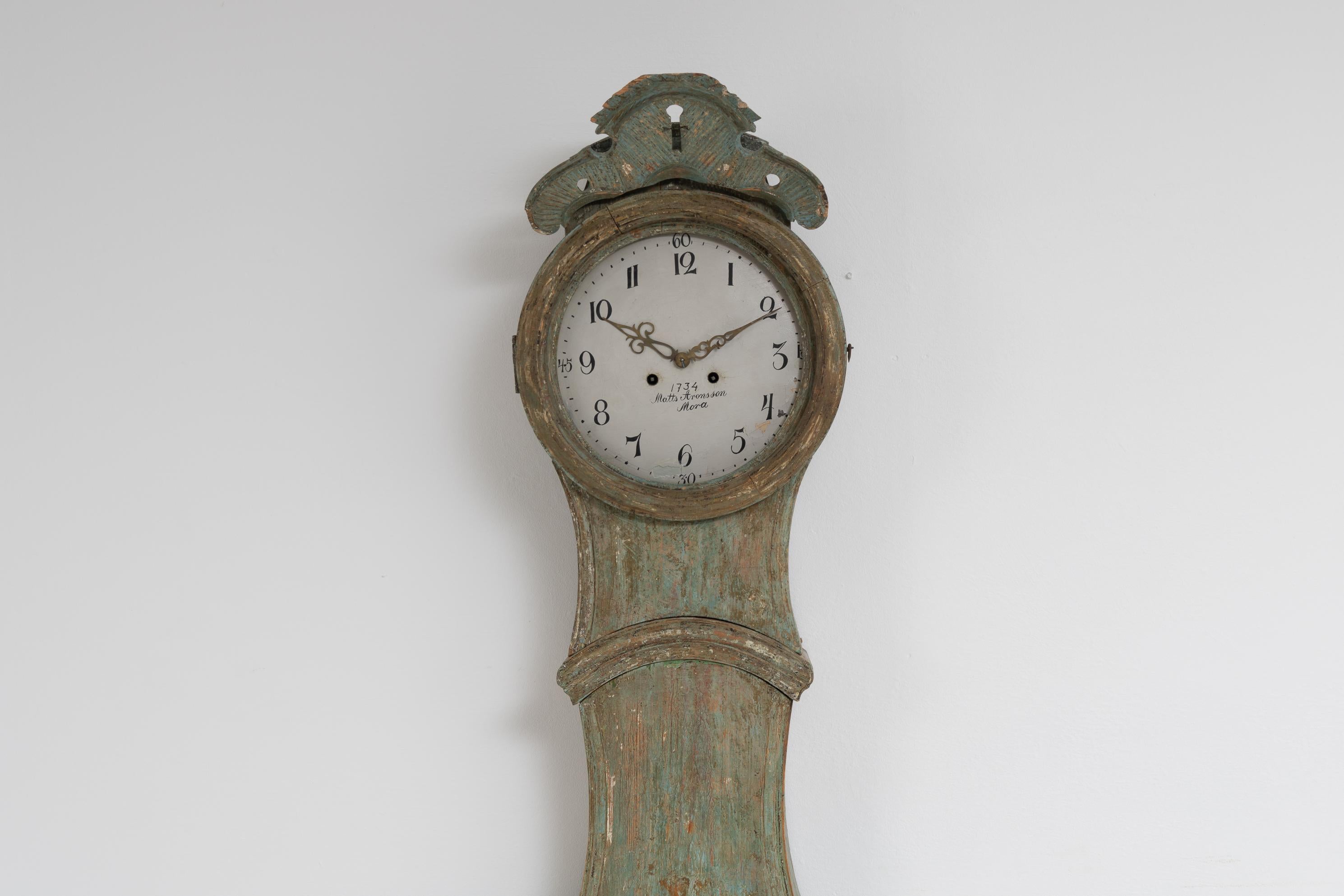 Horloge suédoise classique à long boîtier provenant de la province de Medelpad, dans le nord de la Suède. Fabriqué vers 1820 avec la forme rococo classique et des décorations en bois sculpté à la main. La décoration en forme de coquille au sommet de