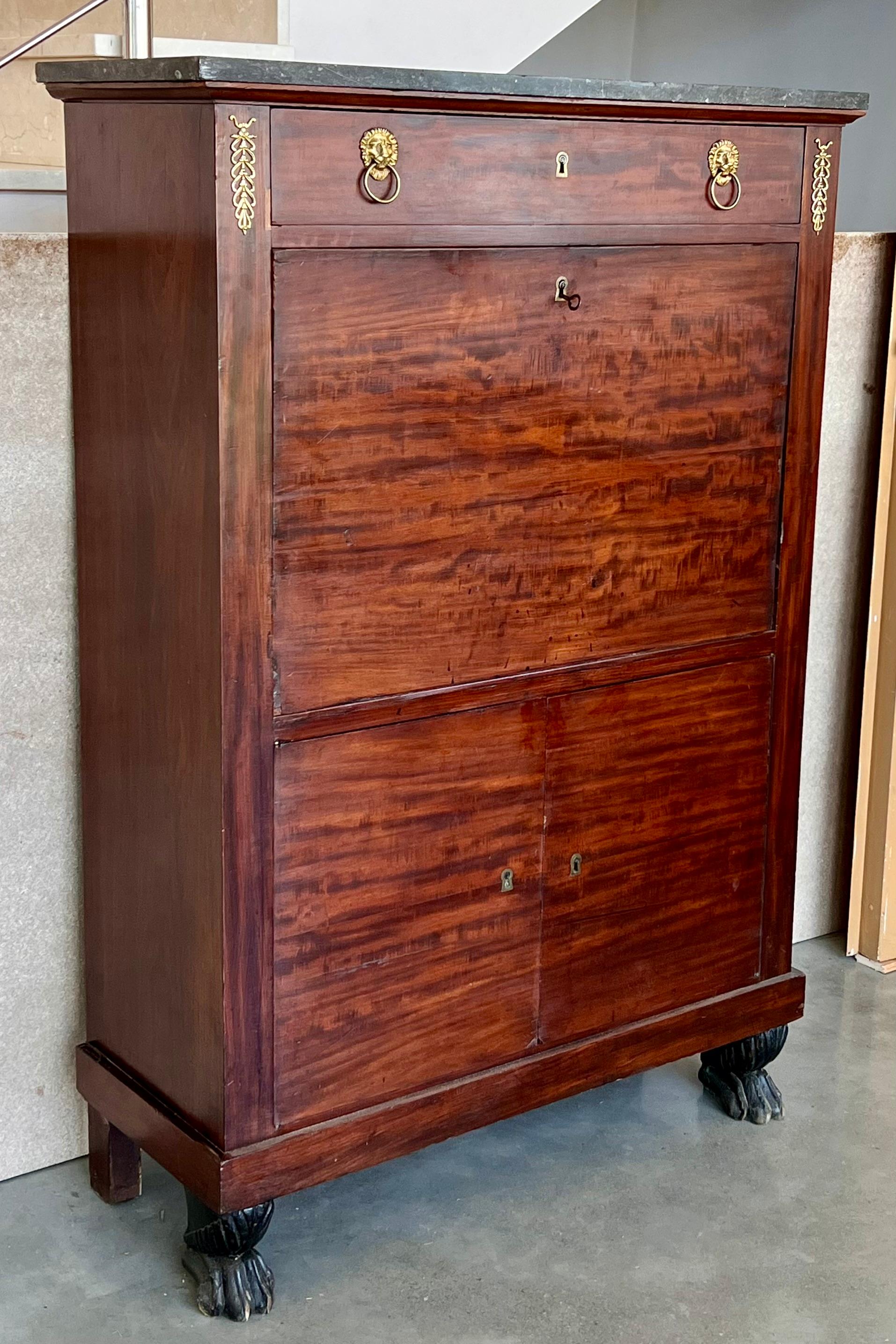 A dramatic Charles X fall front secretary in astounding burled mahogany veneer. The original fossilized marble top is supported by an elliptical molding. The main body contains one upper drawer and seven below the desk area. The secretary workspace
