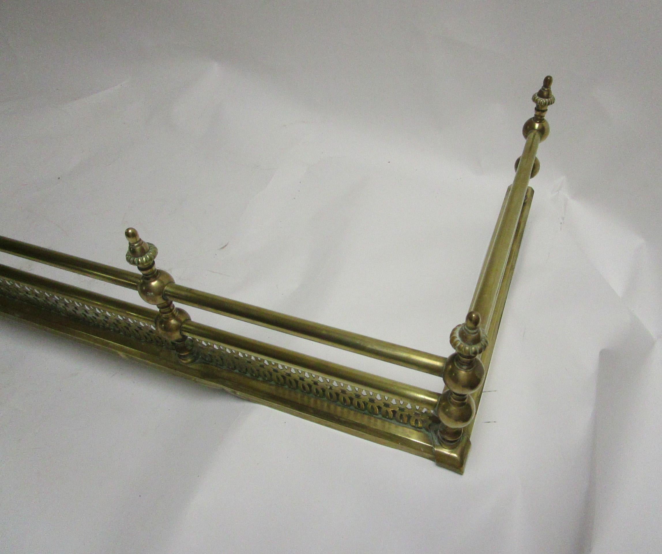 Classic Regency period brass fender having a reticulated frame work. A handsome solid piece in a large size. Inside measurements 59 inches wide x 15.75 deep. Over-all measurements below.