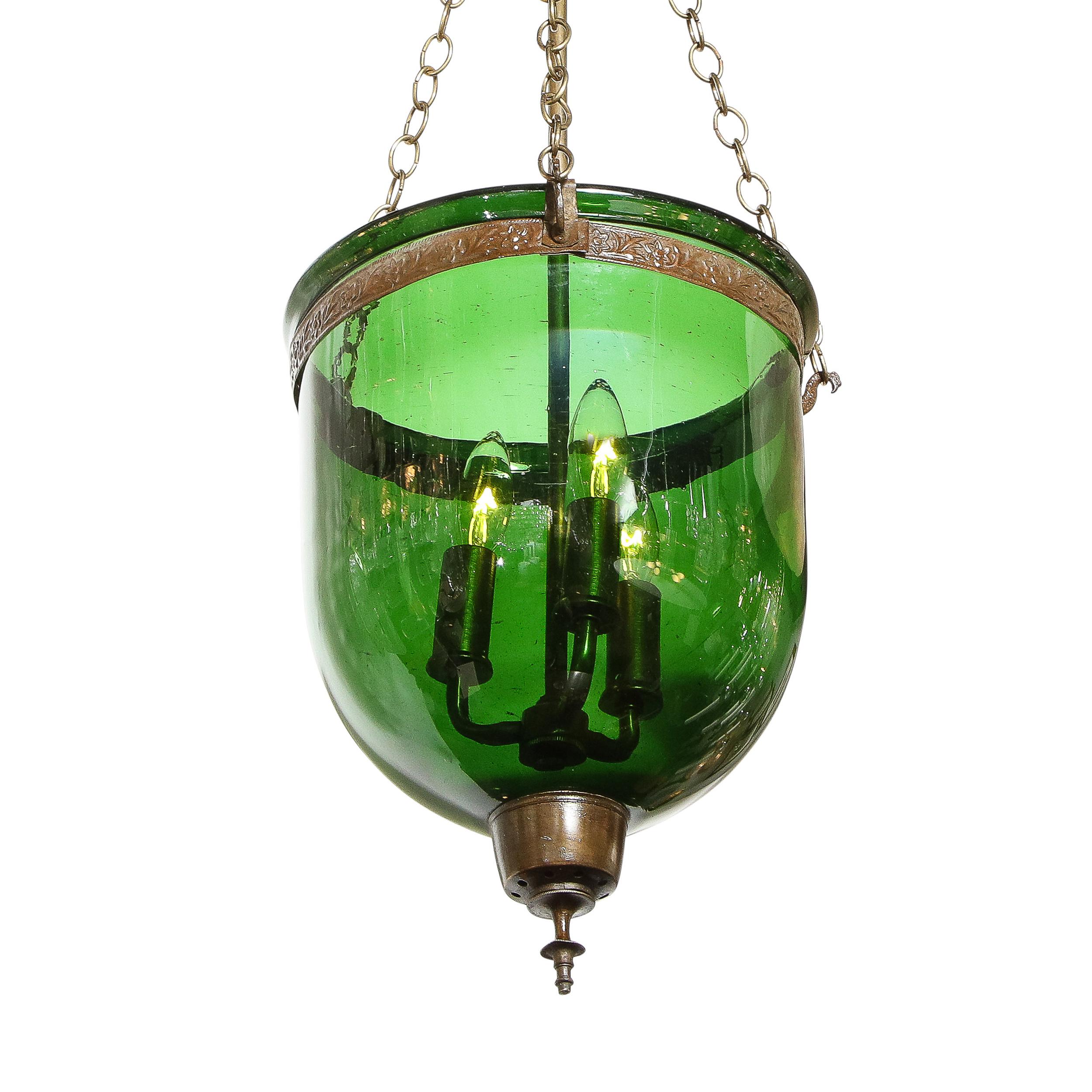 This stately classical pendant was realized in Russia during the 19th century. It features a domed translucent body blown in a rich emerald green glass; a sculptural undulating finial in bronze; the original chain and canopy (also in bronze); and a