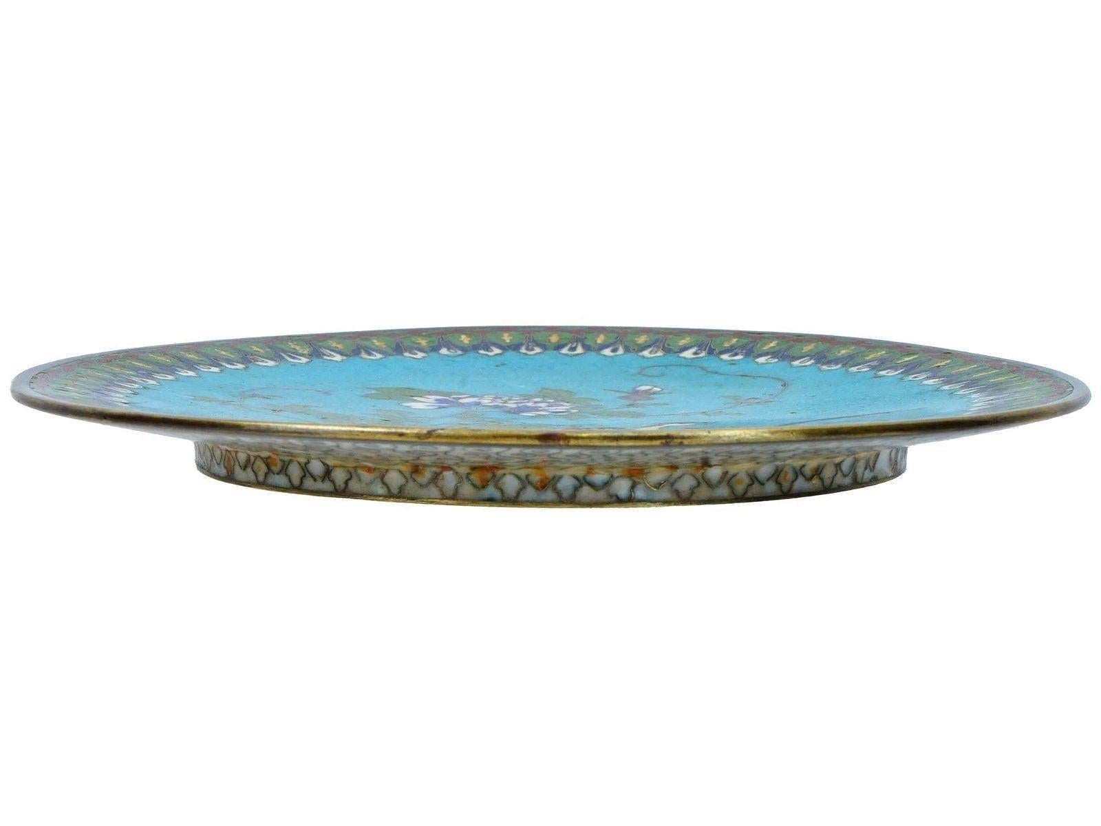 Lovely plate with fine cloisonne enamel designs depicting a peacock on light rocky ground and turquoise colored sky.