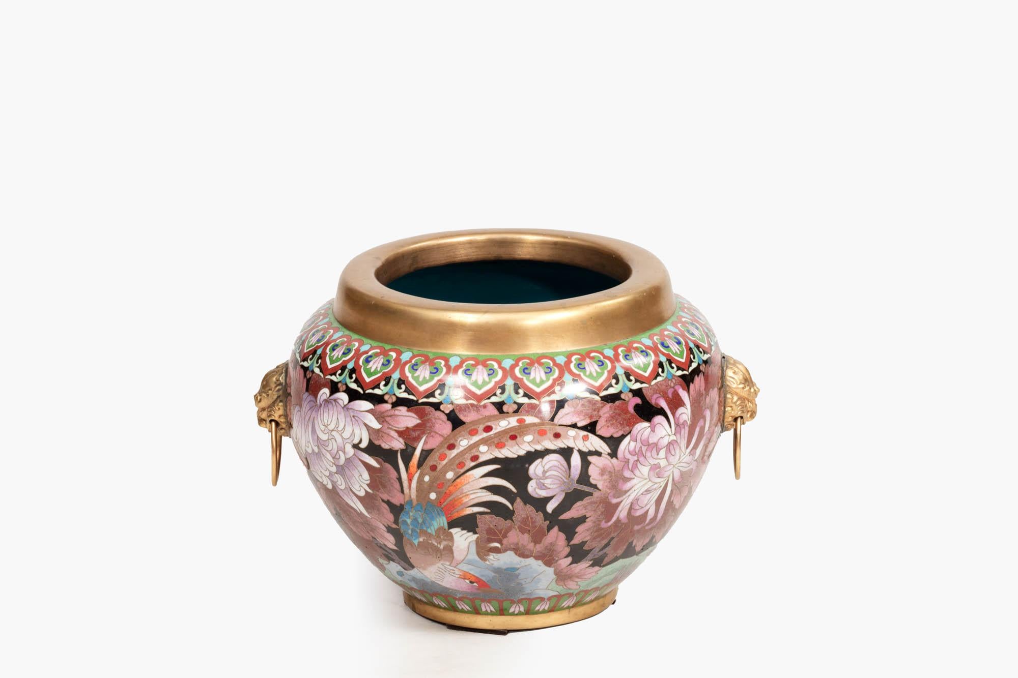 19th century Cloisonné vase richly decorated with bright Oriental patterning, chrysanthemum flowers, and birds. Topped with a gold rim, and featuring a bright blue interior, two sides are flanked with golden lion mask handles.

Cloisonné is a way