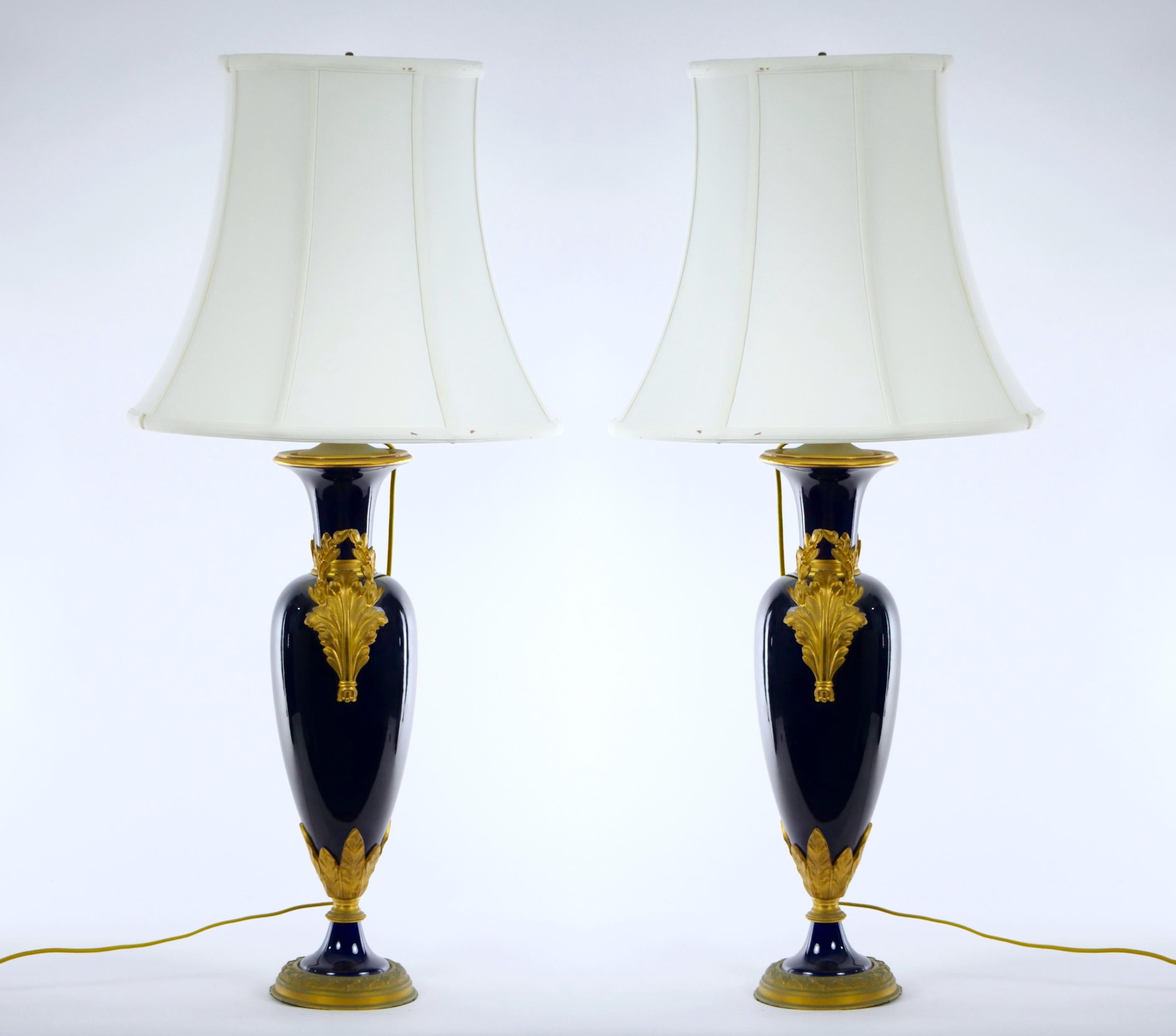 Paire de lampes en porcelaine française du XIXe siècle de style Louis XVI en porcelaine de Sèvres bleu cobalt et bronze doré en forme de vase monté en lampe. Chaque  La lampe présente une forme de vase en urne avec un col étroit et une base avec des