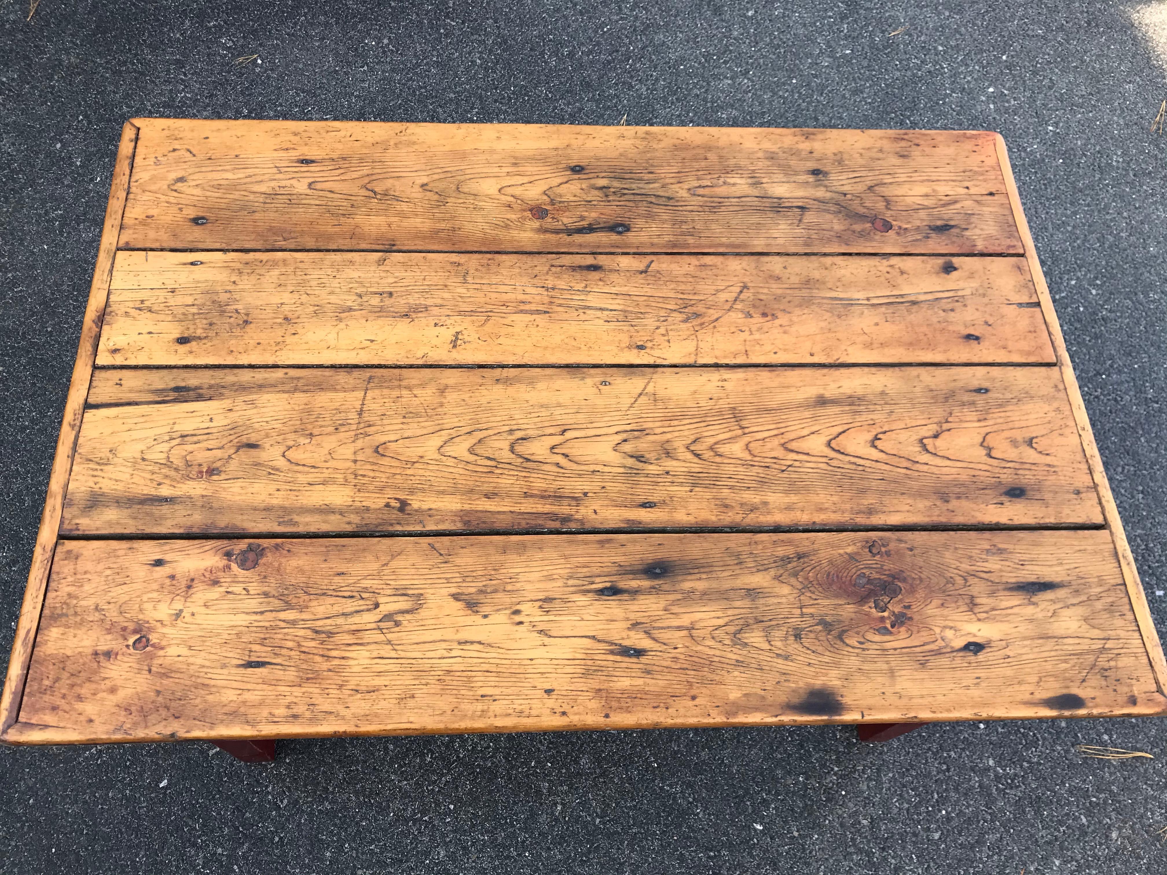 Jolie table du 19ème siècle réduite à la hauteur d'une table basse. Avec un plateau de quatre planches en finition naturelle et une base peinte en rouge. Canada, probablement Terre-Neuve.
