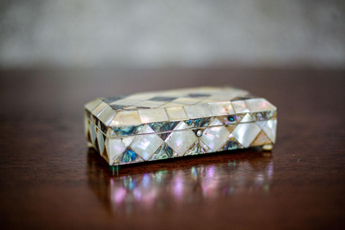We present you a low wooden coffret, whose surface is covered with diamond-shaped mother of pearl tiles.
This item is from Q3 of the 19th century.
The mother of pearl is made of two types of seashell.
Furthermore, the inside is lined with claret