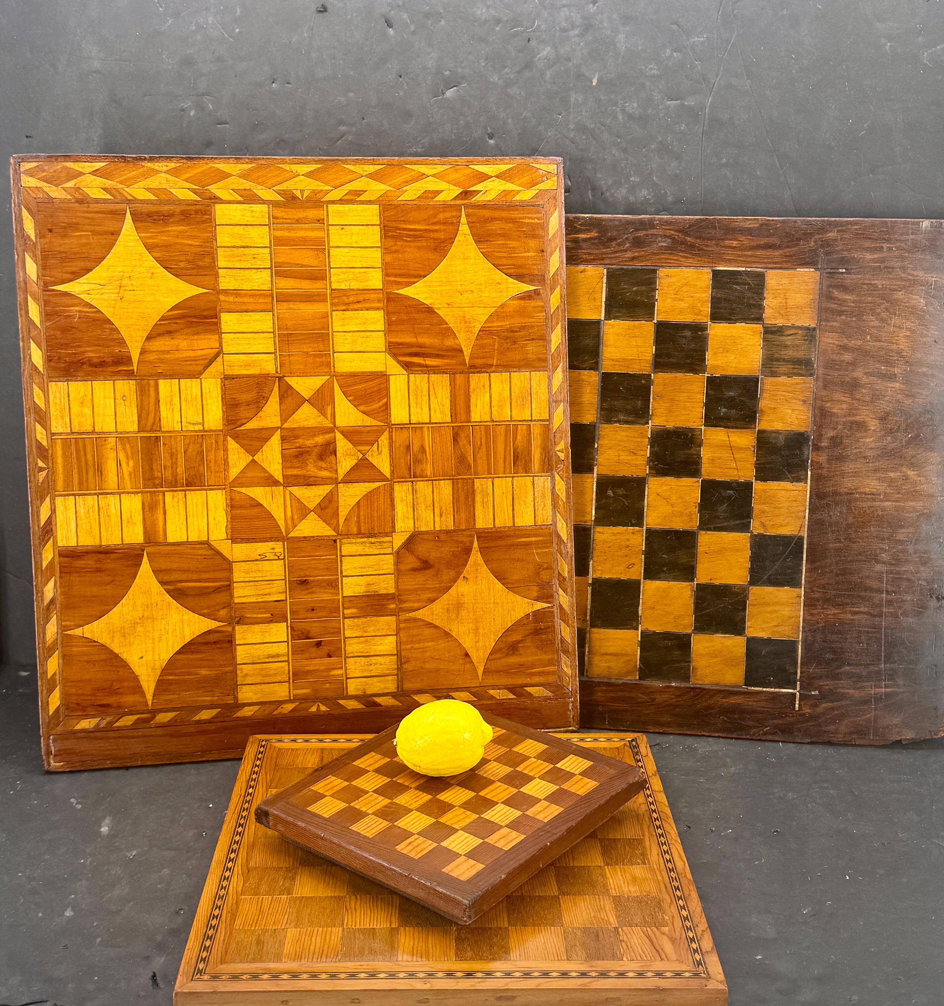 Beeindruckende Sammlung von 4 antiken primitiven hölzernen Spielbrettern mit drei einseitigen Schachbrettern und einem doppelseitigen, das auf der anderen Seite ein Schachbrett und ein Parcheesi-Brett enthält. Die Größen der Einlegeplatten