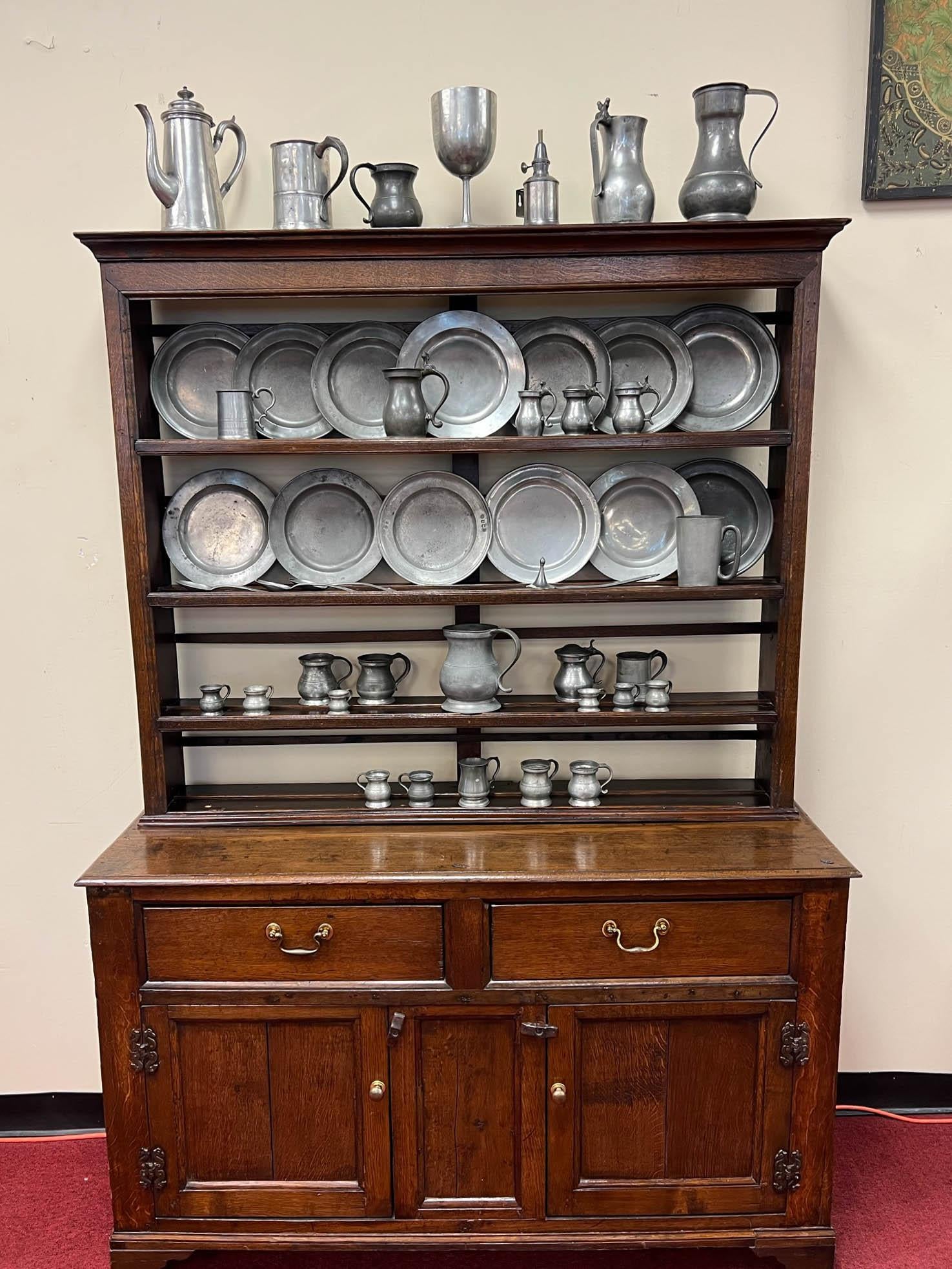 This 19th Century Colonial walnut hutch is in its original condition. The hutch consists of 2 pieces (an upper shelving piece and a lower cabinet). The above open setback shelving features four display levels; the lower cabinet has two drawers and a