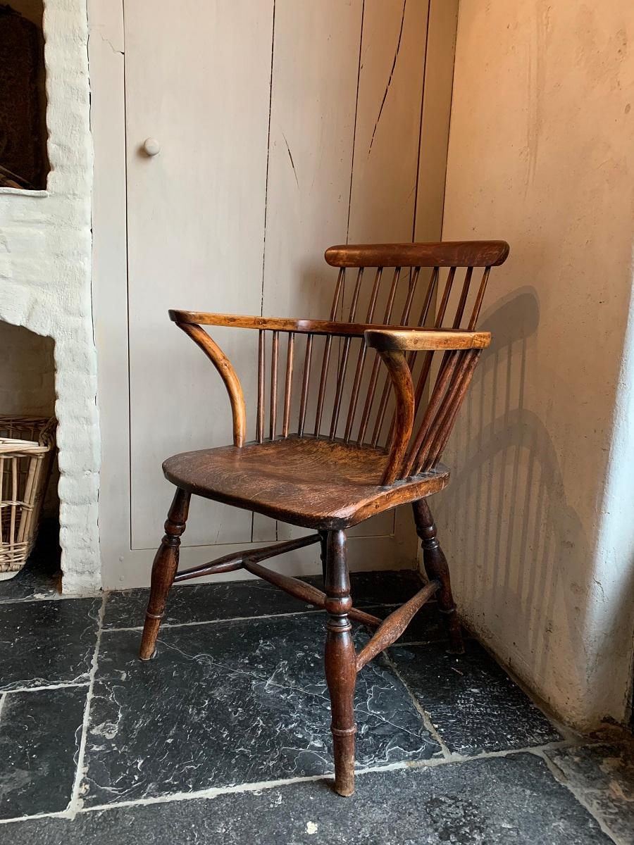 A rare early 19th century Windsor chair with a low comb back and widened armrest. All original with a one slab elm seat. As good as they get...