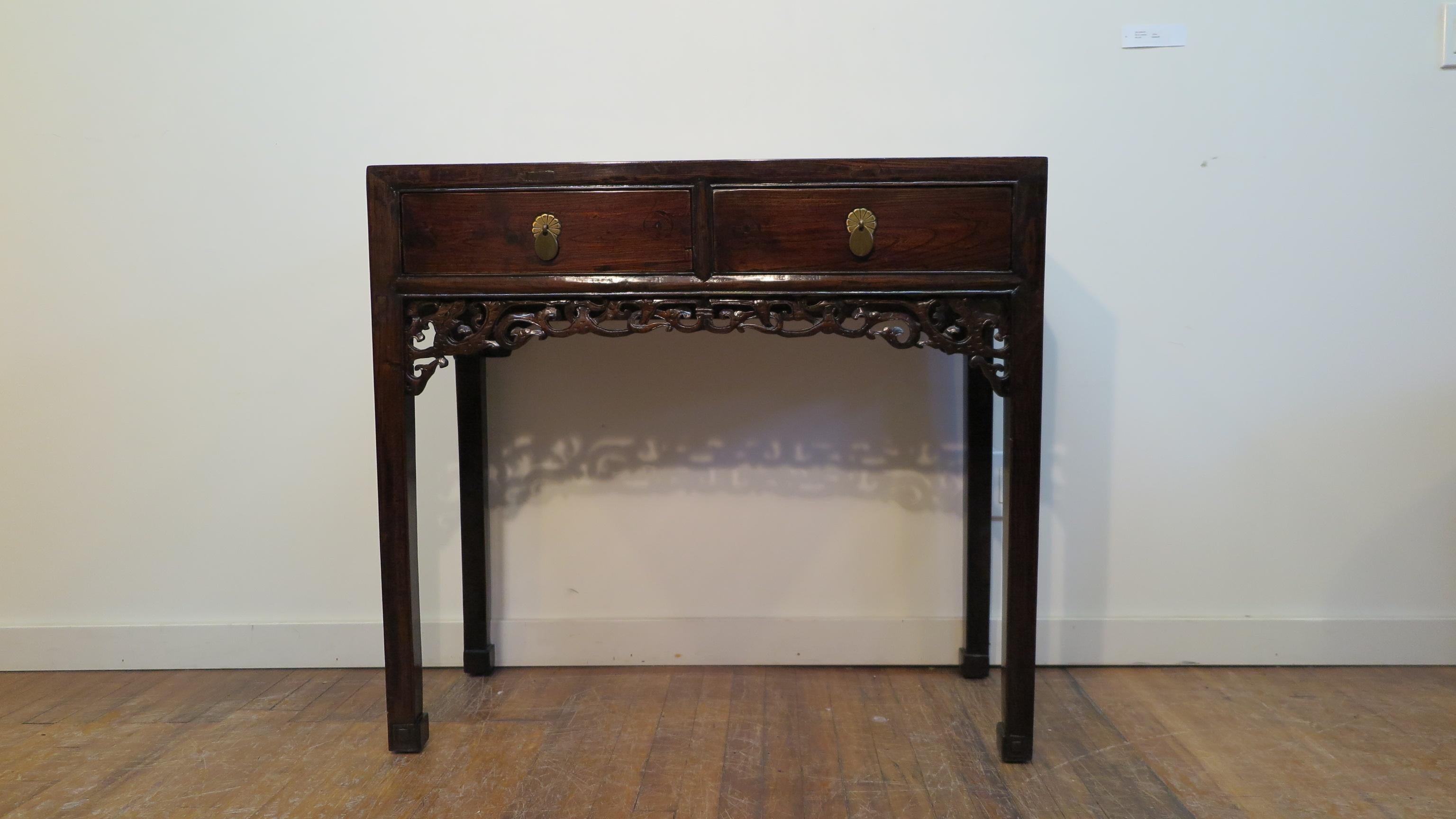 19th century Chinese console table late Qing Dynasty. Elm wood with traditional joinery and lacquered finish.  Emphasizing the tables refinement are two drawers with carved detail apron, brass drawer pulls, and legs terminating to block carved