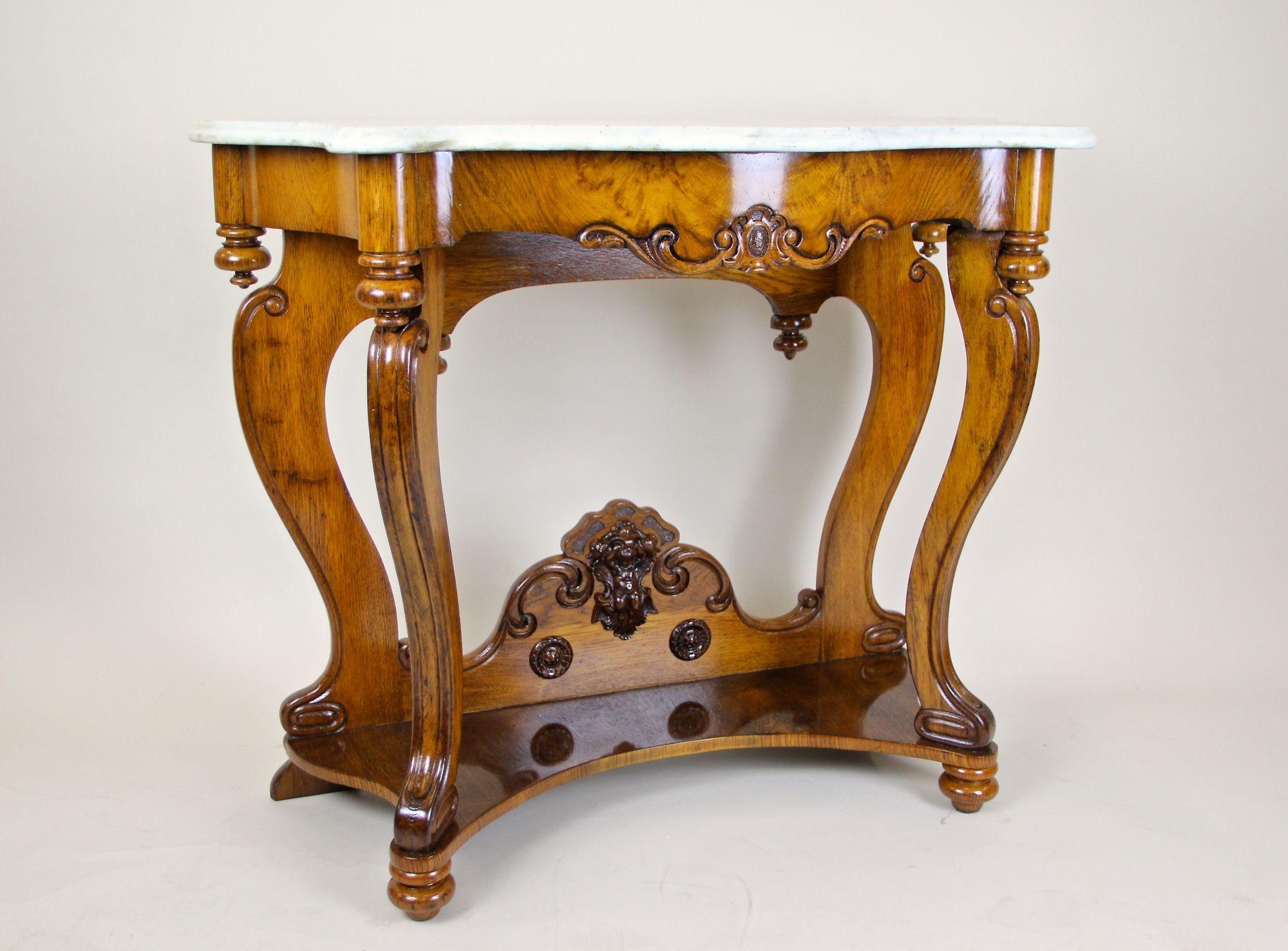 Artfully crafted 19th century oakwood console table with beautiful white/ grey carrara marble plate from the famous Louis Philippe period in France around 1850. Elaborately handcarved out of fine oakwood - partly solid/ partly veneered - this
