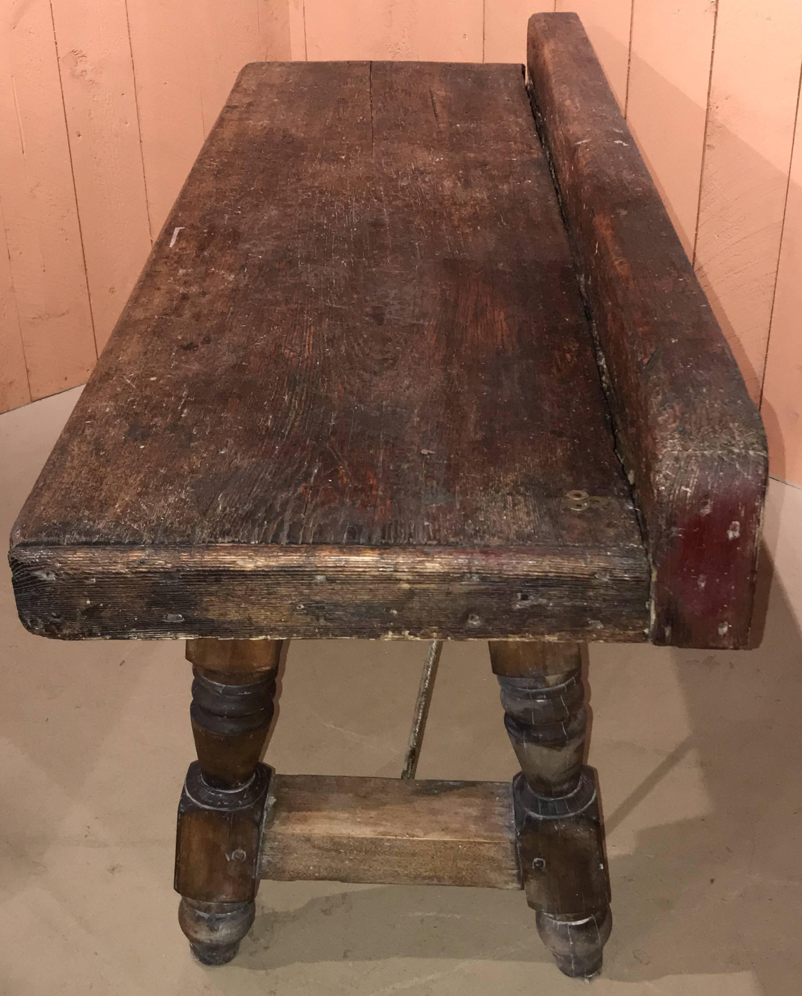 A fabulous counter, workbench, or server featuring a rectangle wooden slab with crest rail, splayed turned legs, and iron stretchers, probably in walnut, Continental, dating to the 19th century with great worn patina. The piece is in very good