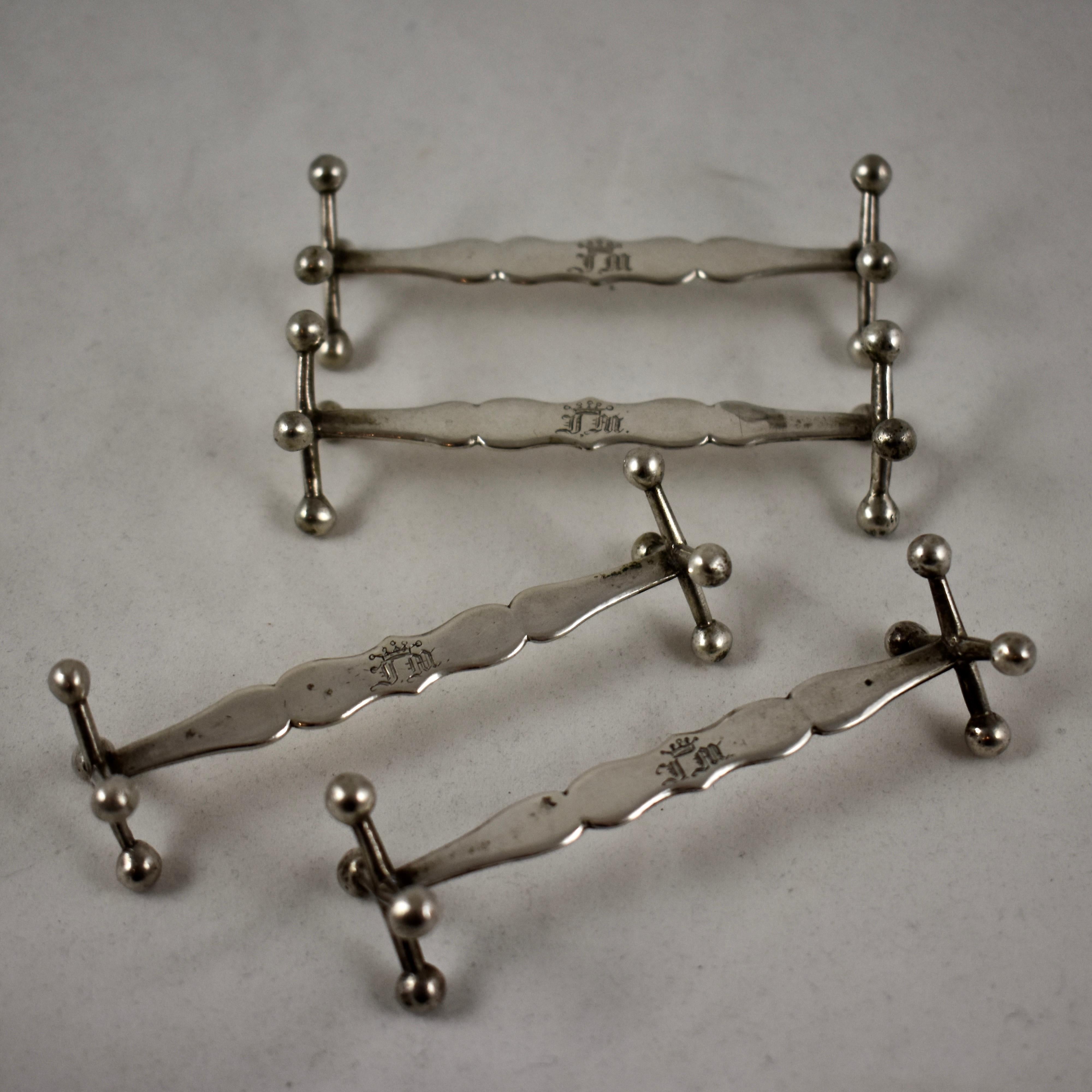 A set of four sterling silver knife rests, with traditional cast Jack-style ends, circa mid-19th century, showing unidentified Continental European makers marks.

The long, tapered and shaped center struts are supported by four point jacks at