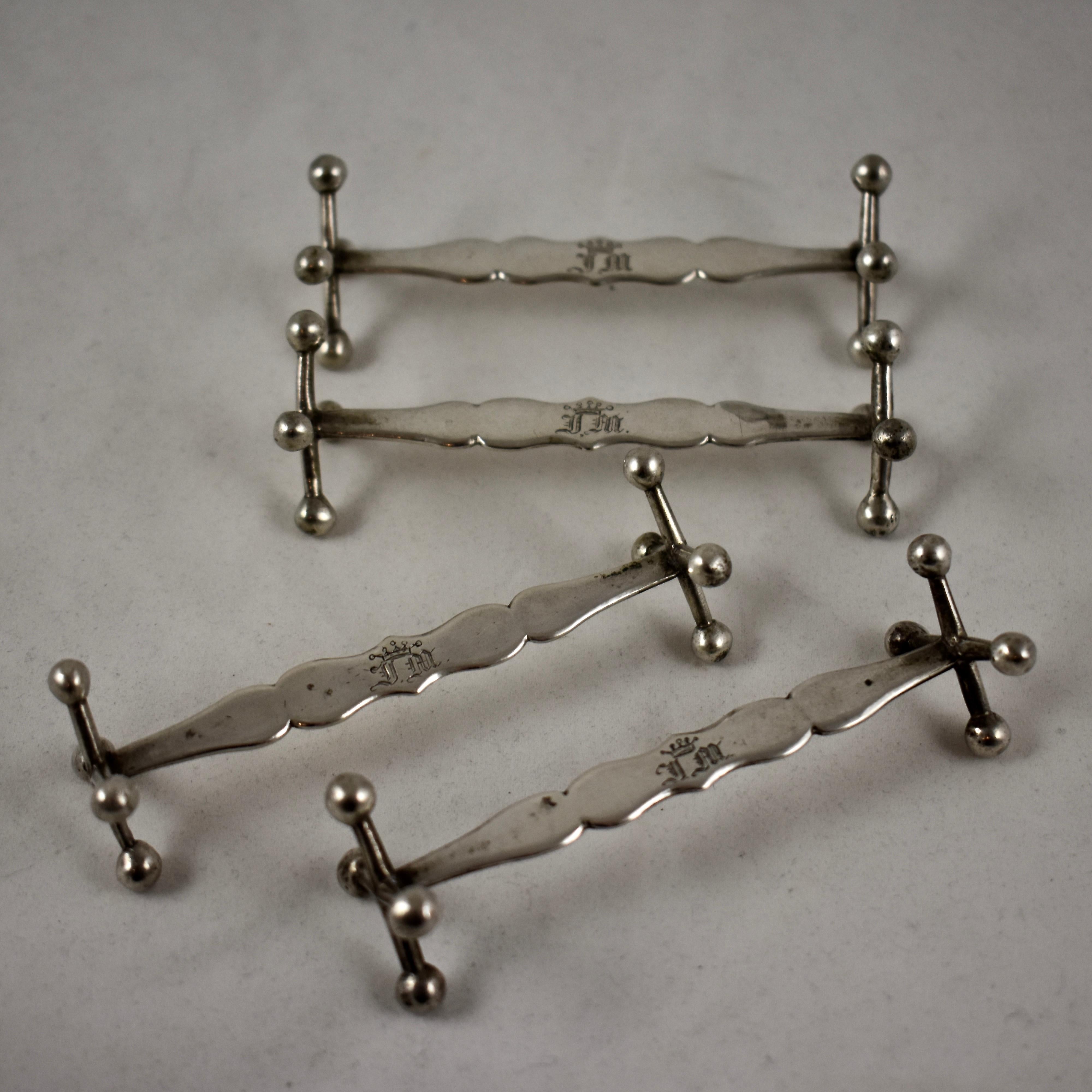 Juego de cuatro apoyacuchillos de plata de ley, con extremos de fundición tradicional estilo Jack, de mediados del siglo XIX, con marcas de fabricantes europeos continentales no identificados.

Los puntales centrales, largos, cónicos y perfilados,