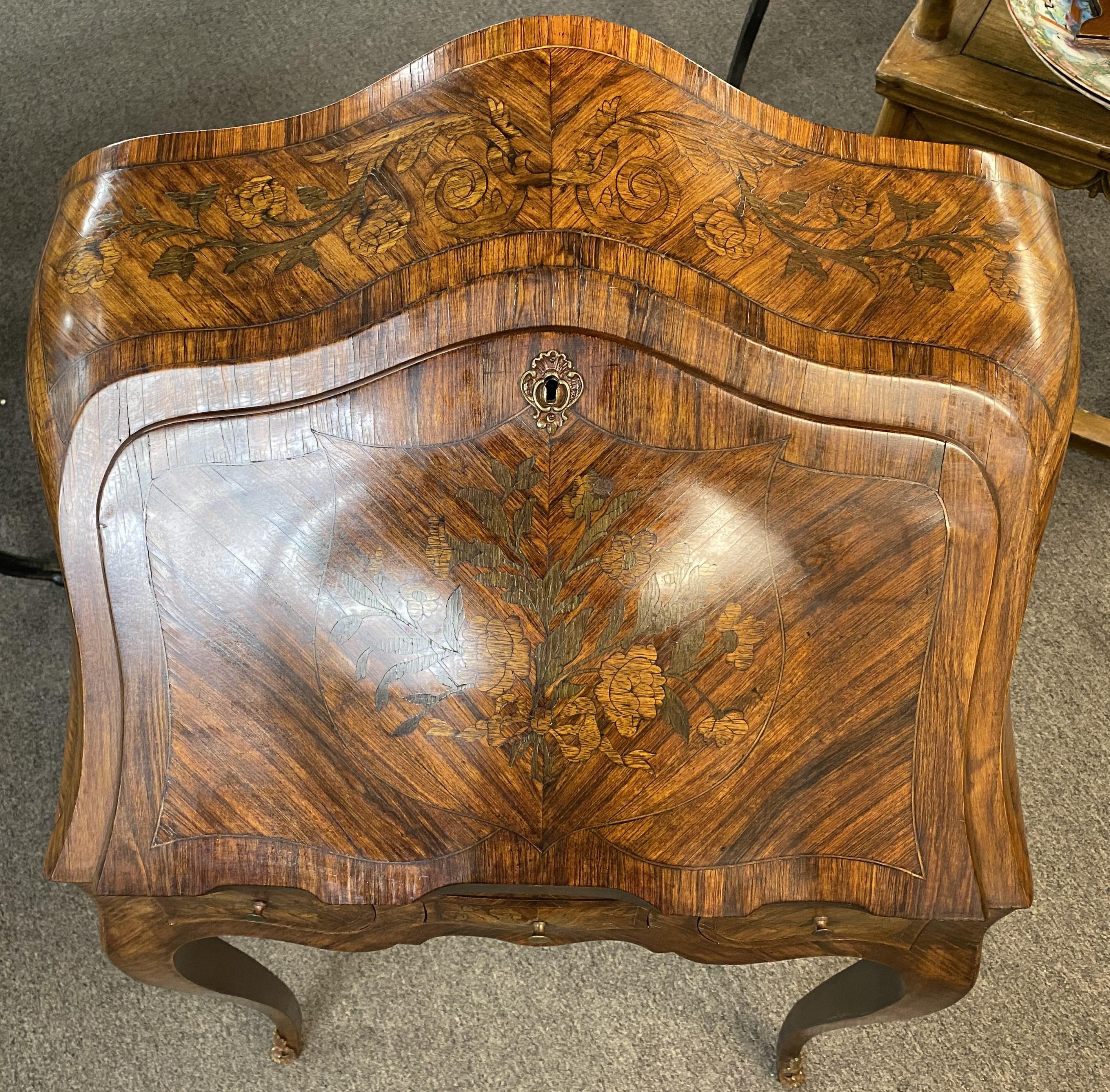 Un bell'esemplare di scrivania continentale in legno di frutto con coperchio intarsiato a fogliame, bordi impiallacciati a fasce incrociate e cassa sagomata, interno a compartimenti staccati con cassetti incastrati, piano di scrittura in pelle