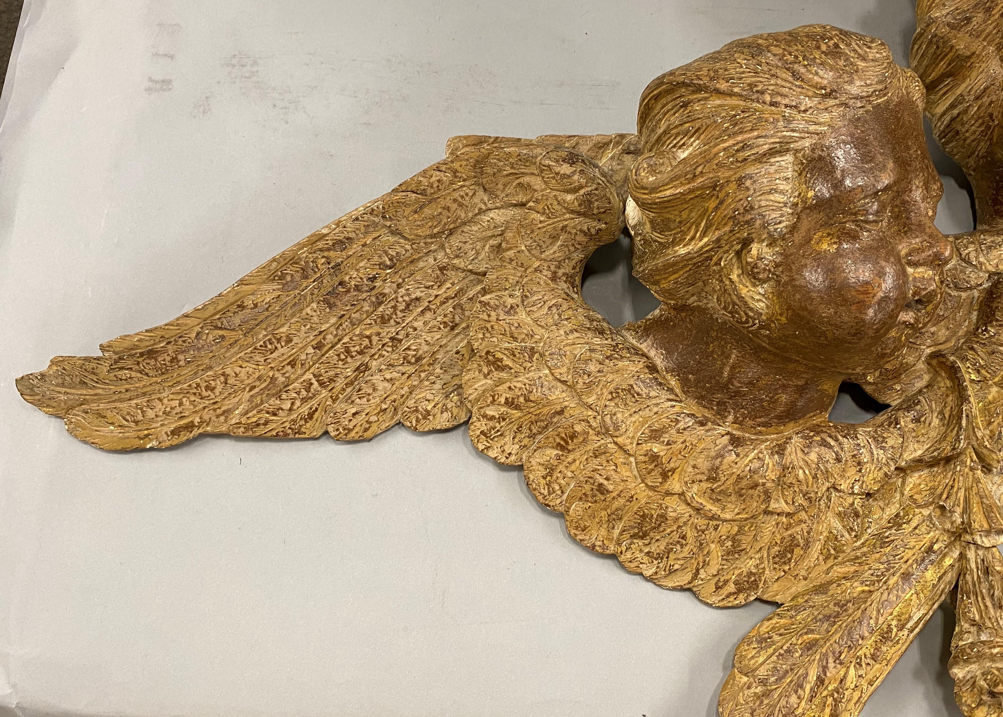 A nicely carved group of three giltwood cherub heads with outstretched wings and foliate accents, probably 19th century Continental (French or Italian) in origin, in very good overall condition, with some gilt losses and high point rubs, as well as