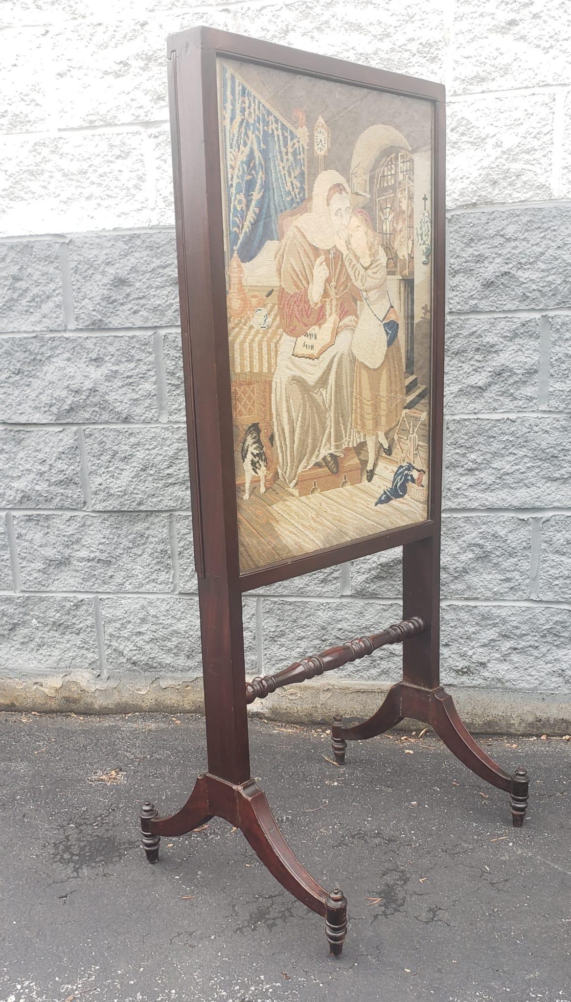 19th century continental mahogany and tapestry expandable trestle fire screen. The handmade tapestry depicts a lady sitting down ( possibly a Nun or Reverend Mother) with holy bible on her laps and embrassing a young girl standing by her side. The