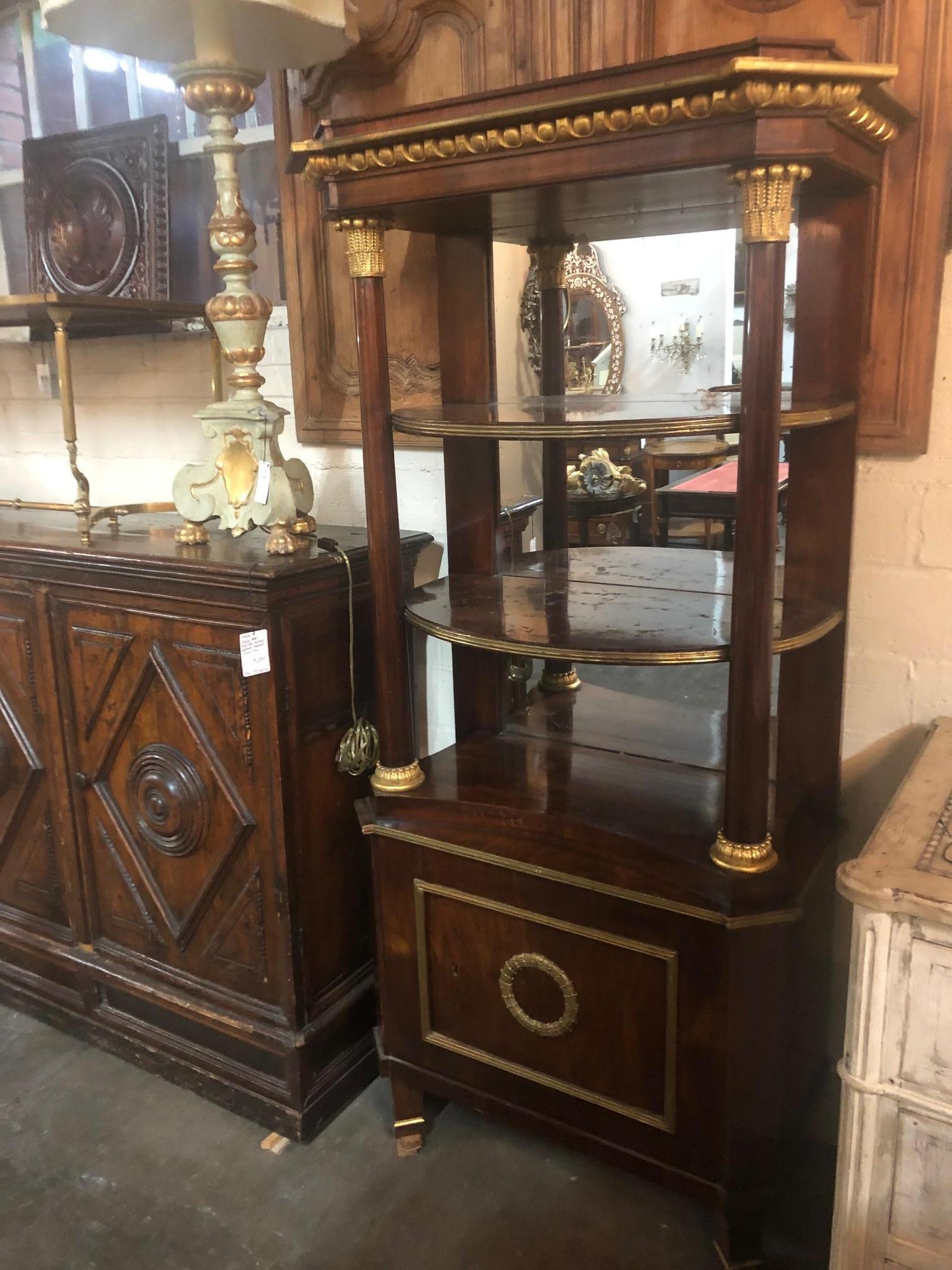 Superb quality and uniquely designed early 19th century neoclassical mahogany étagère with mirrored back. The shaped top above half round open shelves with supporting columns having parcel gilt accents and capitals. The lower portion with a cupboard