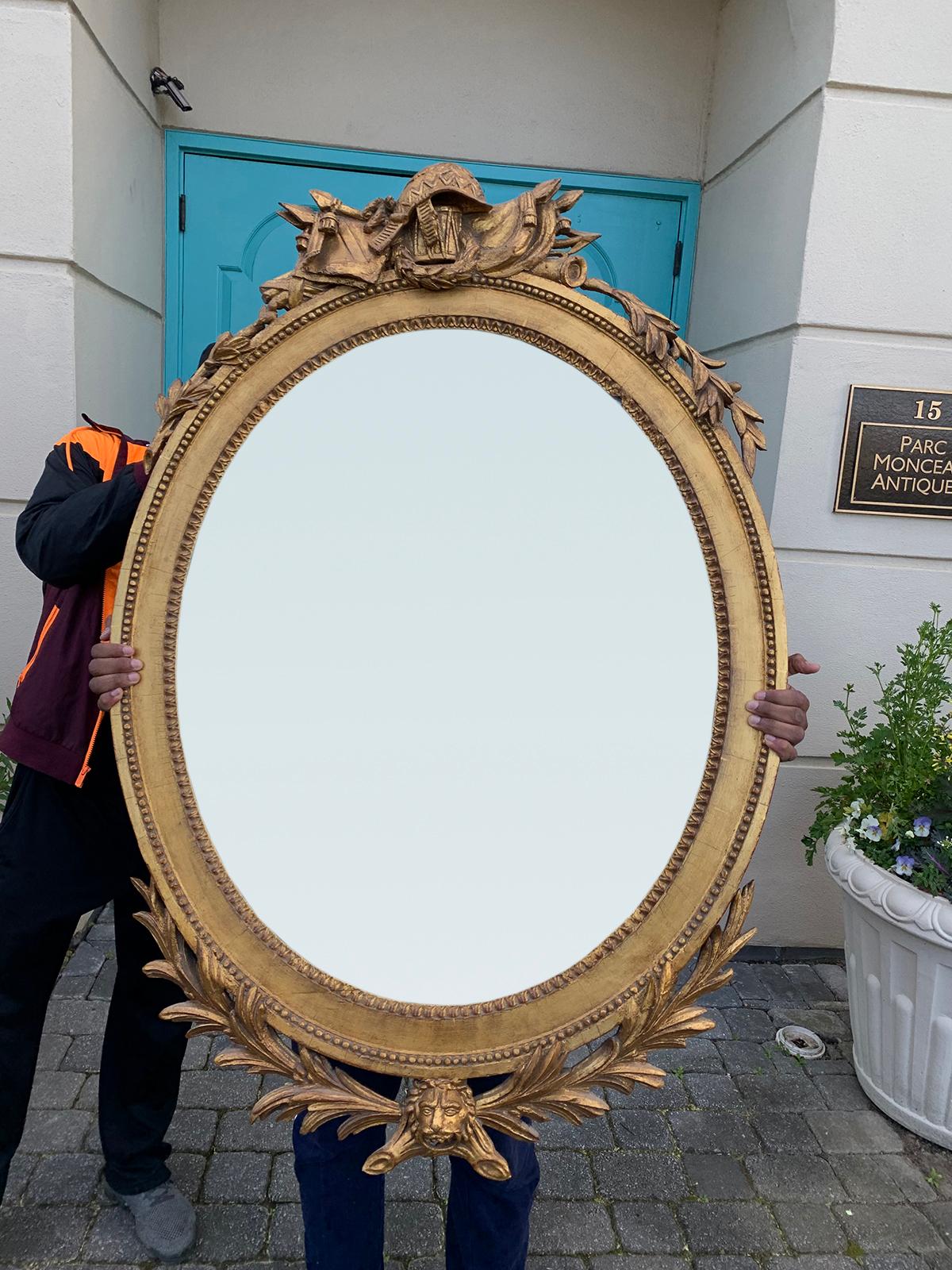 19th century continental oval giltwood mirror with trophy and lion.