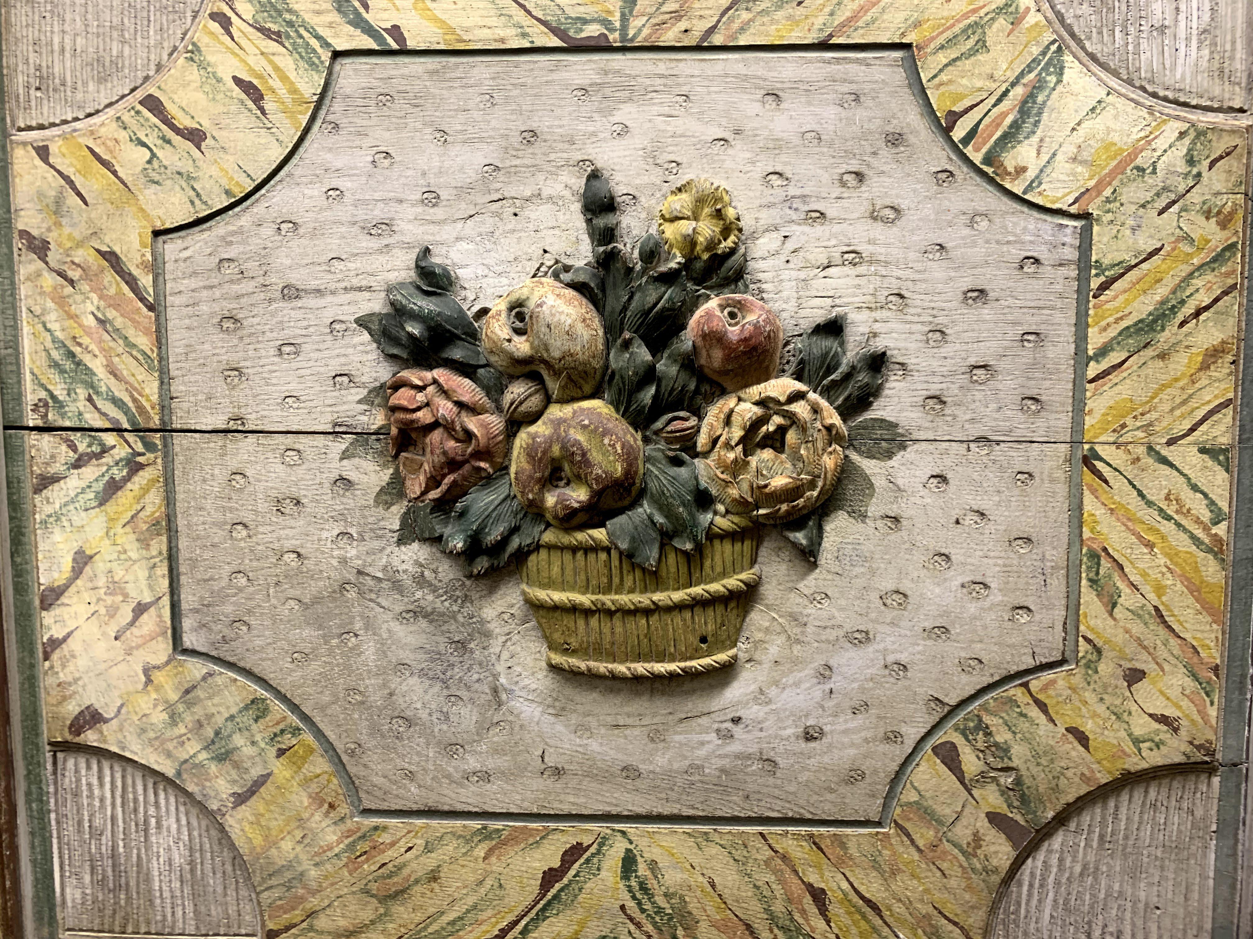 A 19th century Continental polychrome panel with carved casket of fruit and flowers within a marbelized frame with matchstick carved spandrels. Very good overall condition, with minor border losses, minor paint fade or muting, and expected wear from