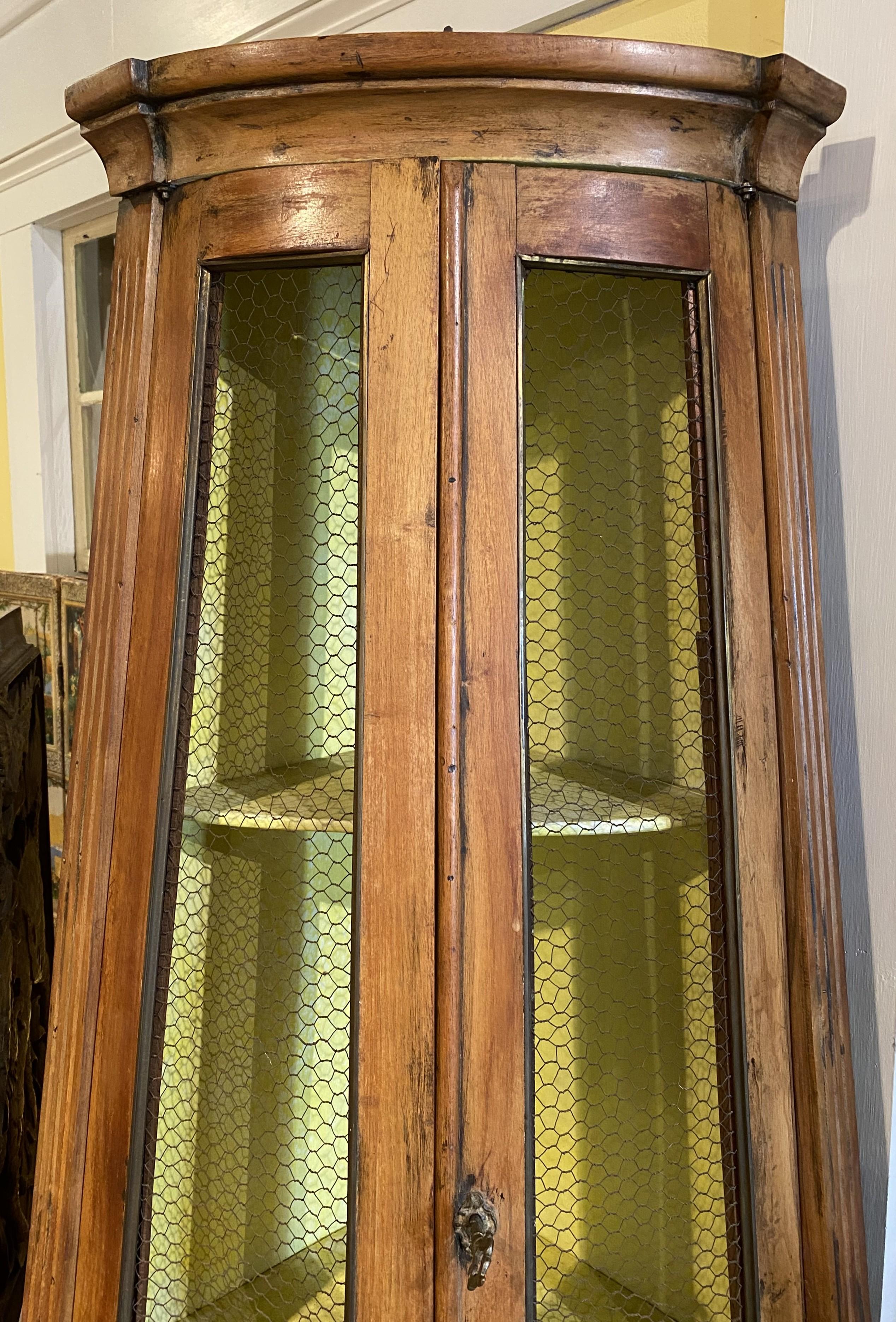 Un bell'esempio di armadio angolare in pino in due parti, con la parte superiore affusolata con due porte a filo, che si aprono su un interno a due ripiani dipinto di giallo, sopra una parte inferiore con due porte a pannelli ciechi, che si aprono